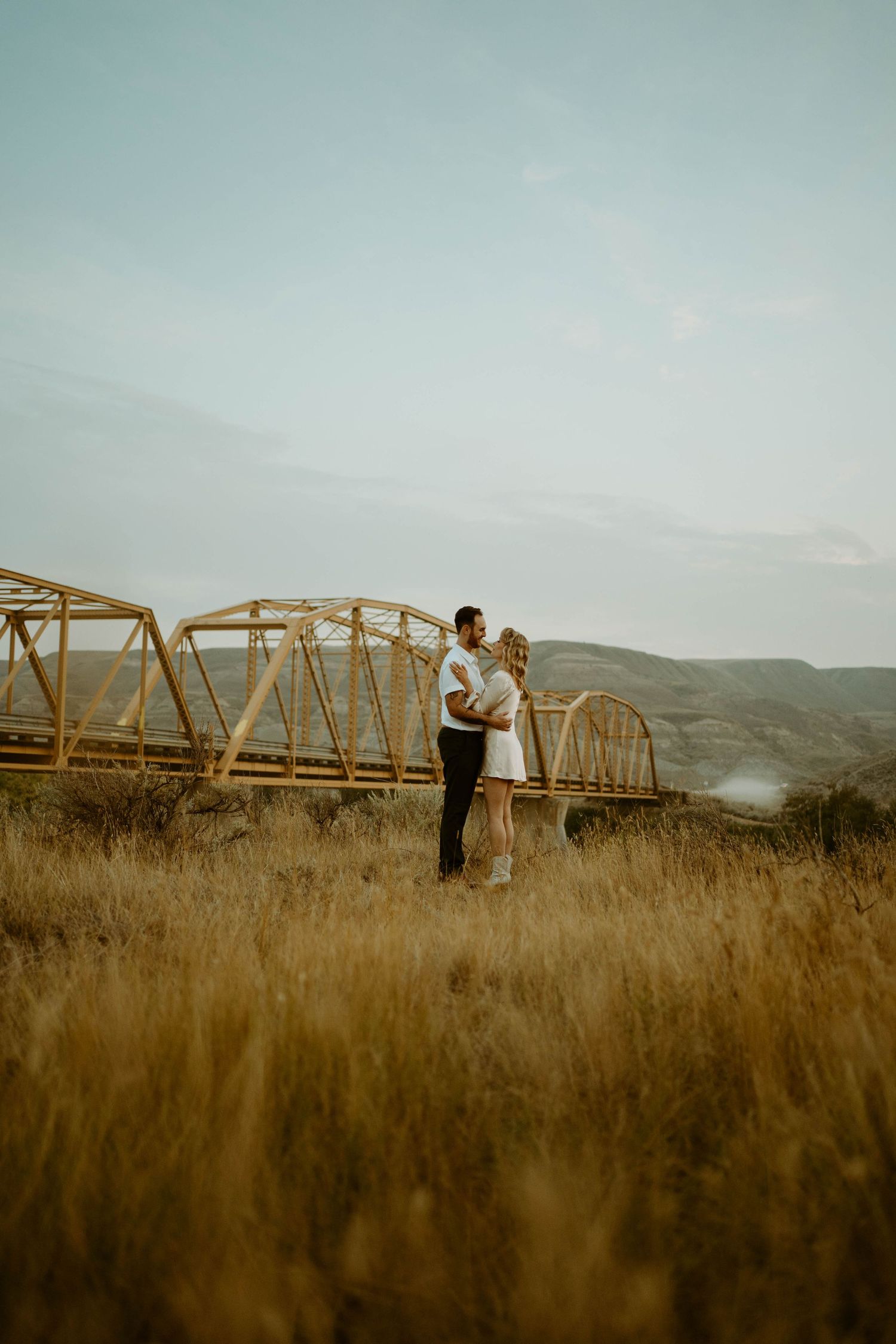 Romantic sunset silhouette against rustic metal bridge structure in golden field in Drumheller, Alberta.