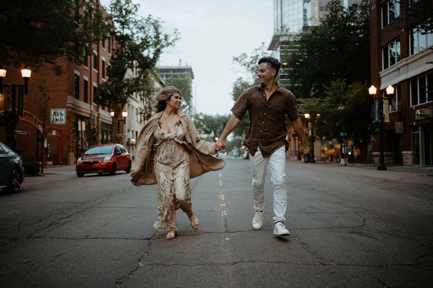 A couple dancing playfully on an empty city street during golden hour.