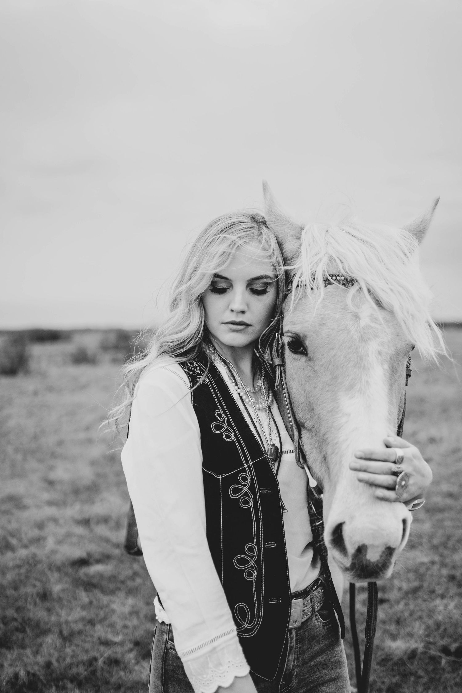 White horse and rider share tender moment in black and white portrait.
