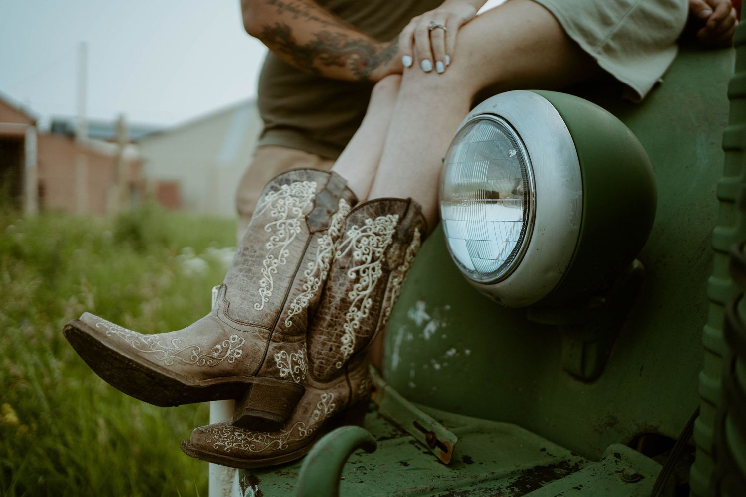 Worn leather cowboy boots rest on green vintage farming equipment in Southern Alberta.
