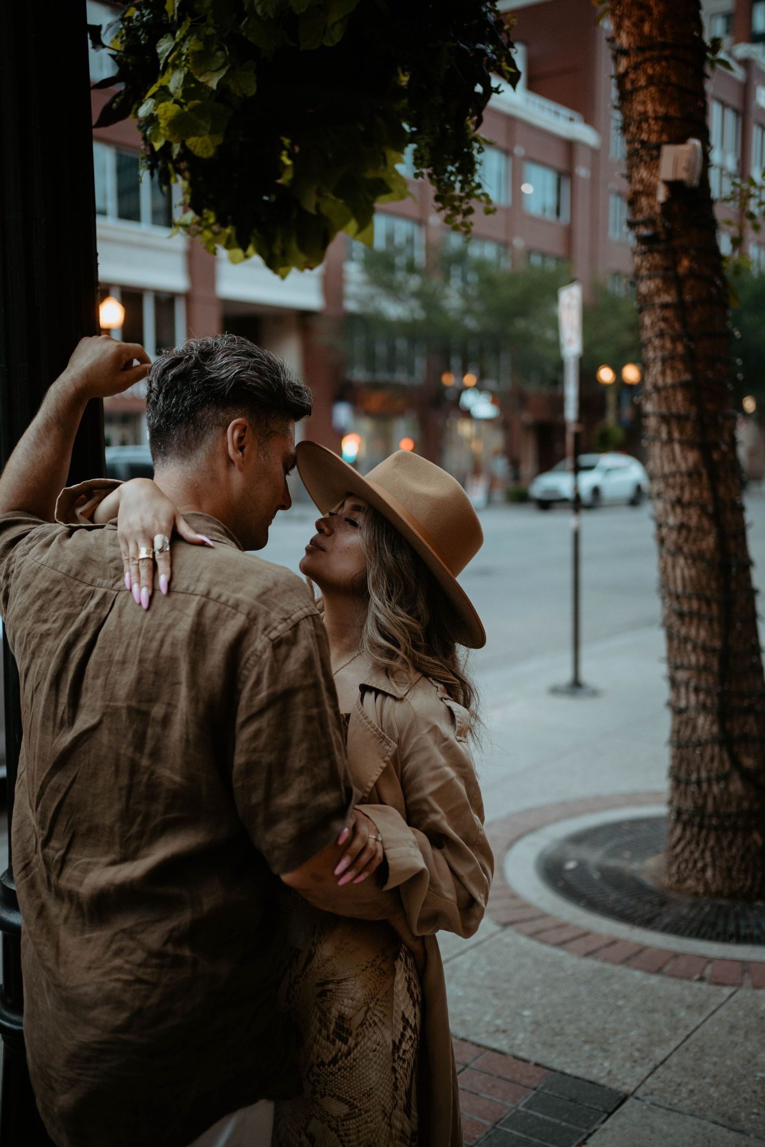 A stylish couple sharing an intimate moment on an urban street at dusk.