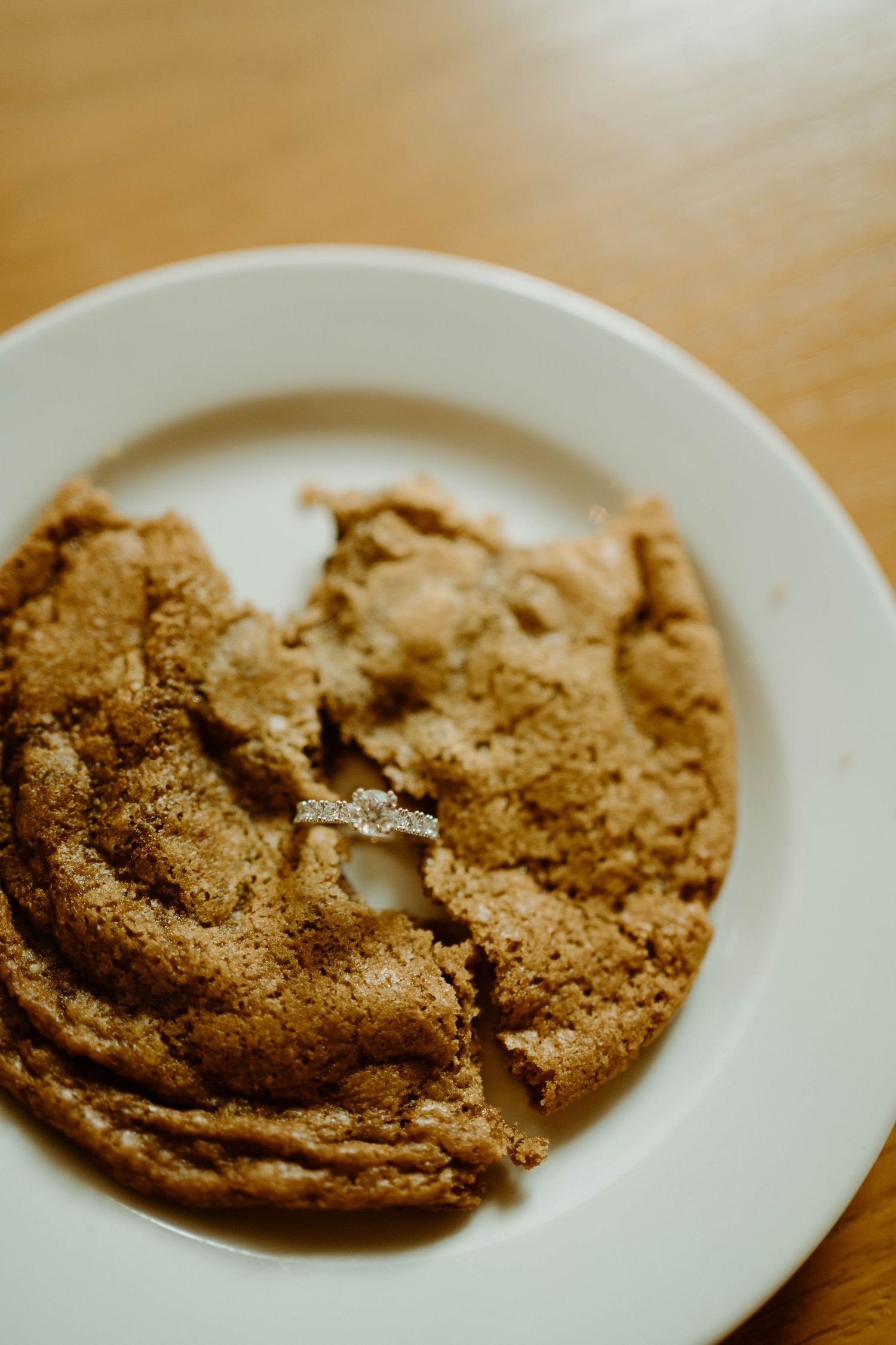 Close-up of a freshly baked golden brown cookie on white plate.