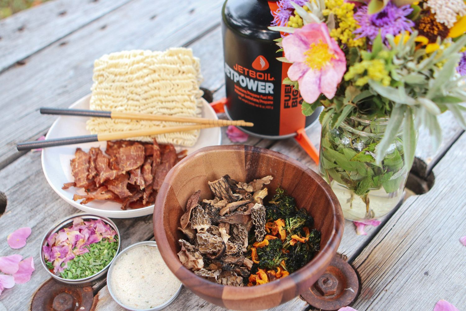 Outdoor dining spread with ramen, flowers, and Brewers sauces.