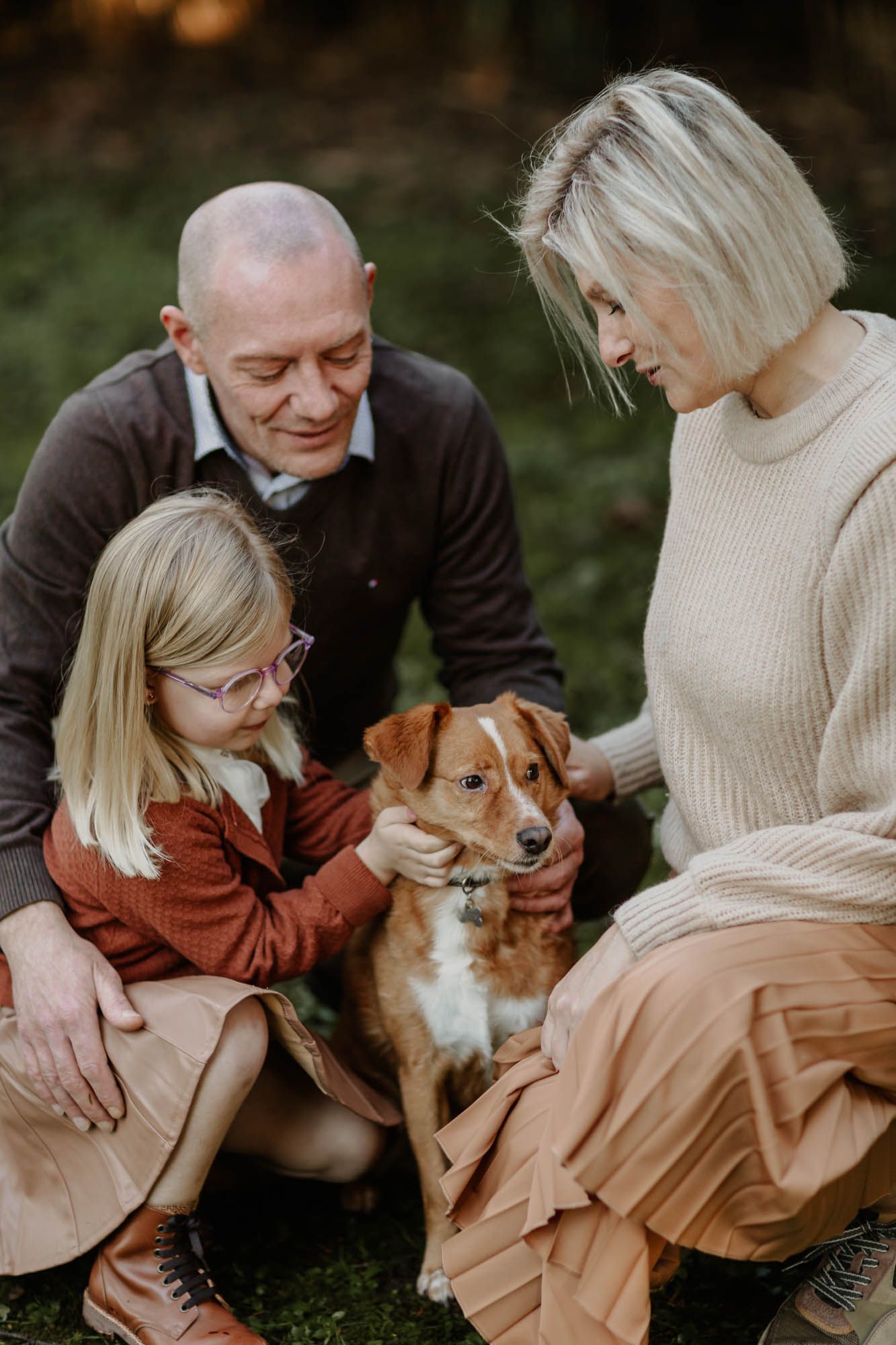 Family portrait in nature featuring a dog and warm autumn colors.