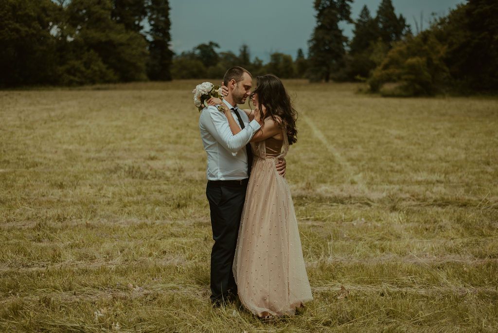 Couple embracing in a sunlit meadow during golden hour.