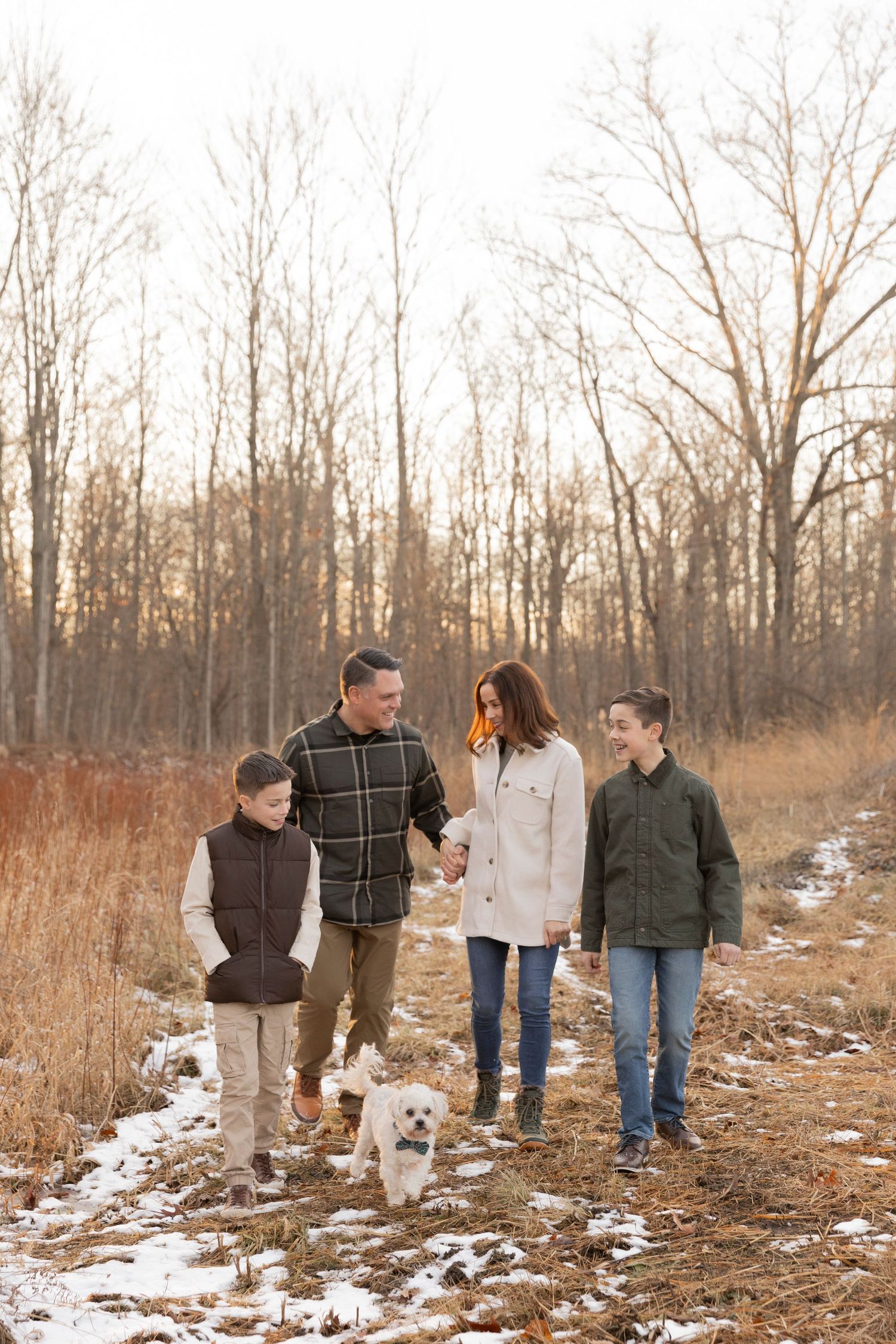 family of four walking in a field of grasses and snow with their dog at Douglas evans nature preserve