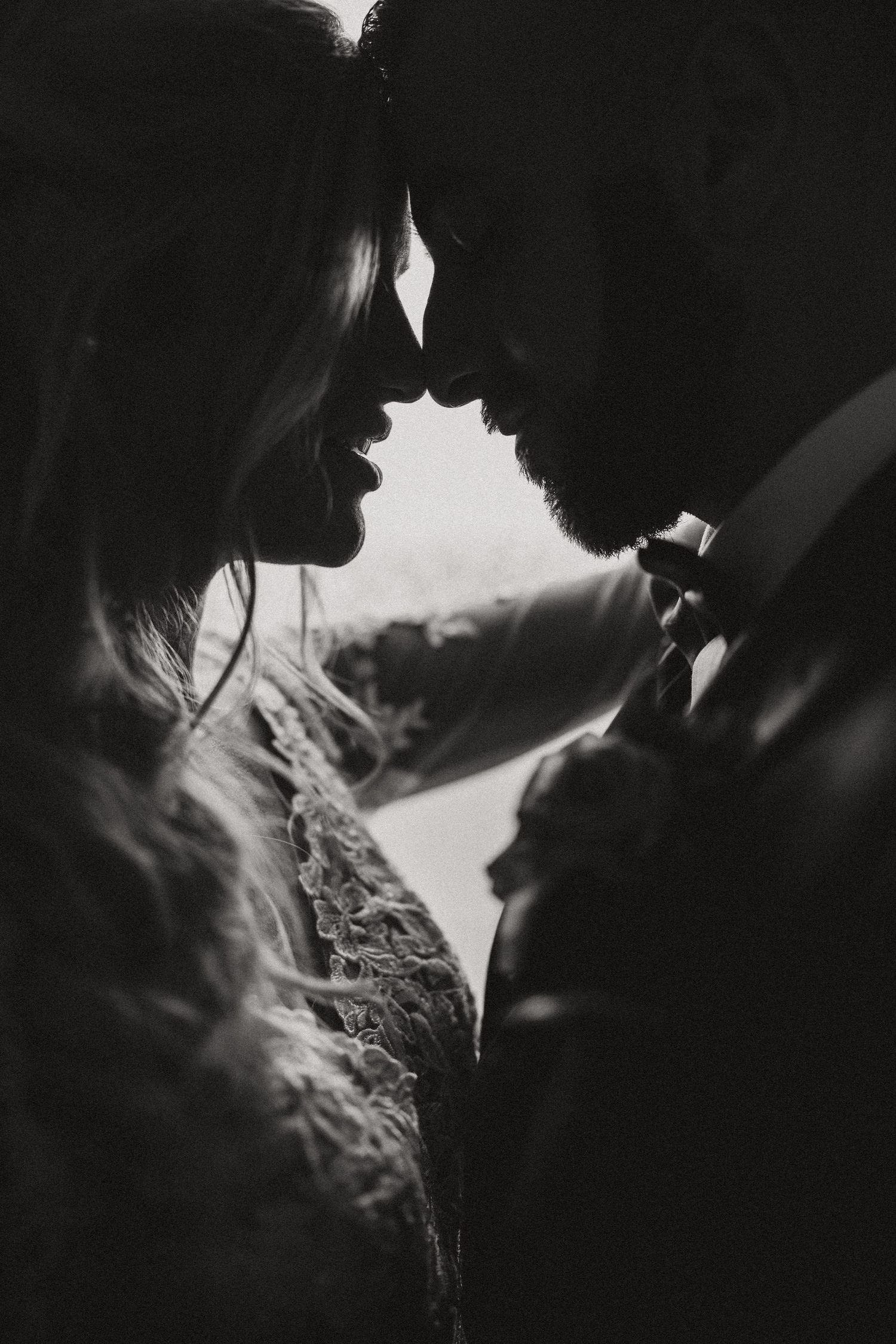 A romantic black and white silhouette of a couple in an intimate moment wearing formal attire.