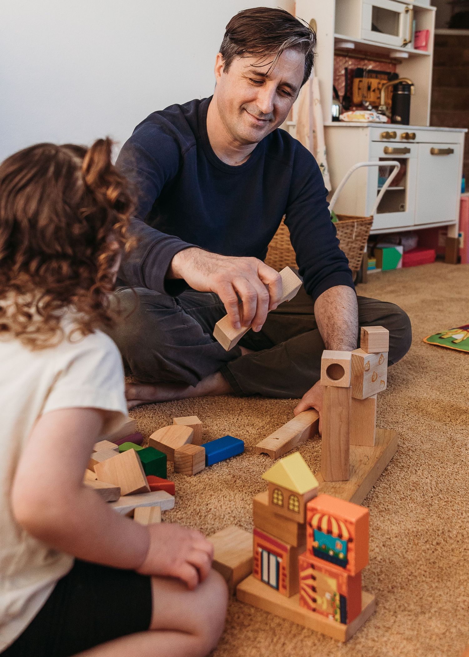 Playing with wooden building blocks and toys on a carpeted floor.