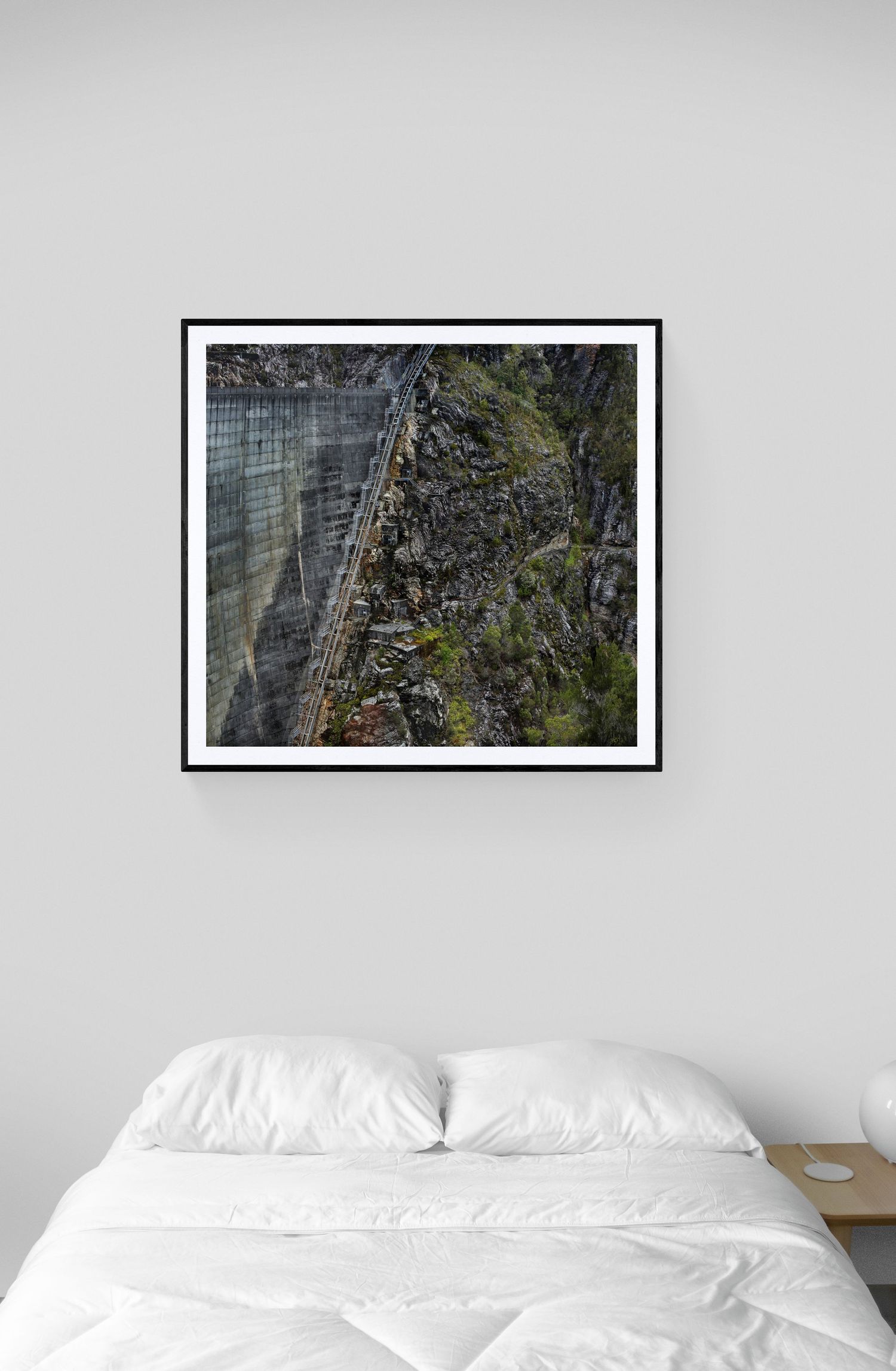Dramatic black and white photograph of a steep mountain wall with industrial infrastructure mounted on rocky terrain.