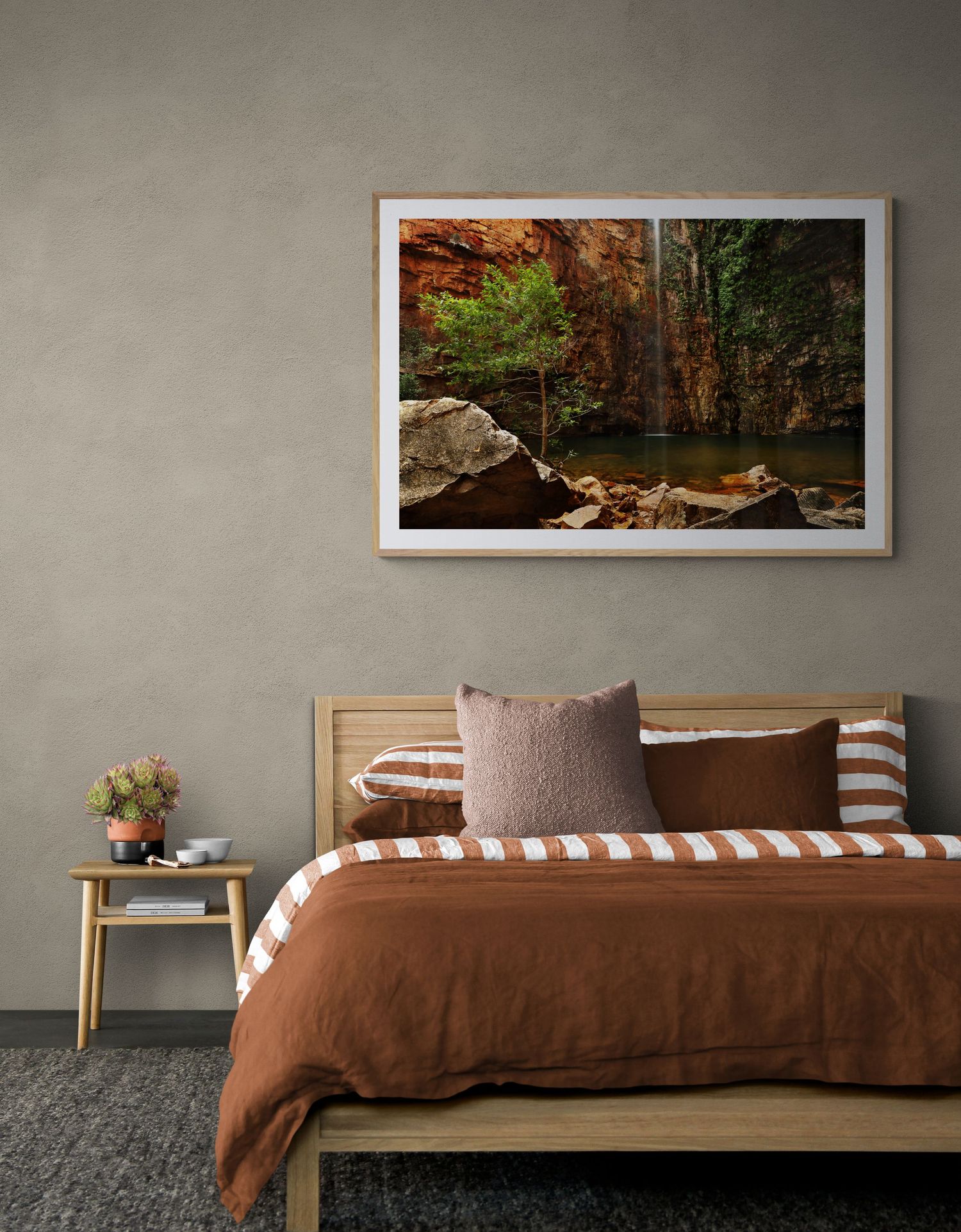 Modern bedroom with rustic nature photograph, brown bedding, and geometric patterned pillows.
