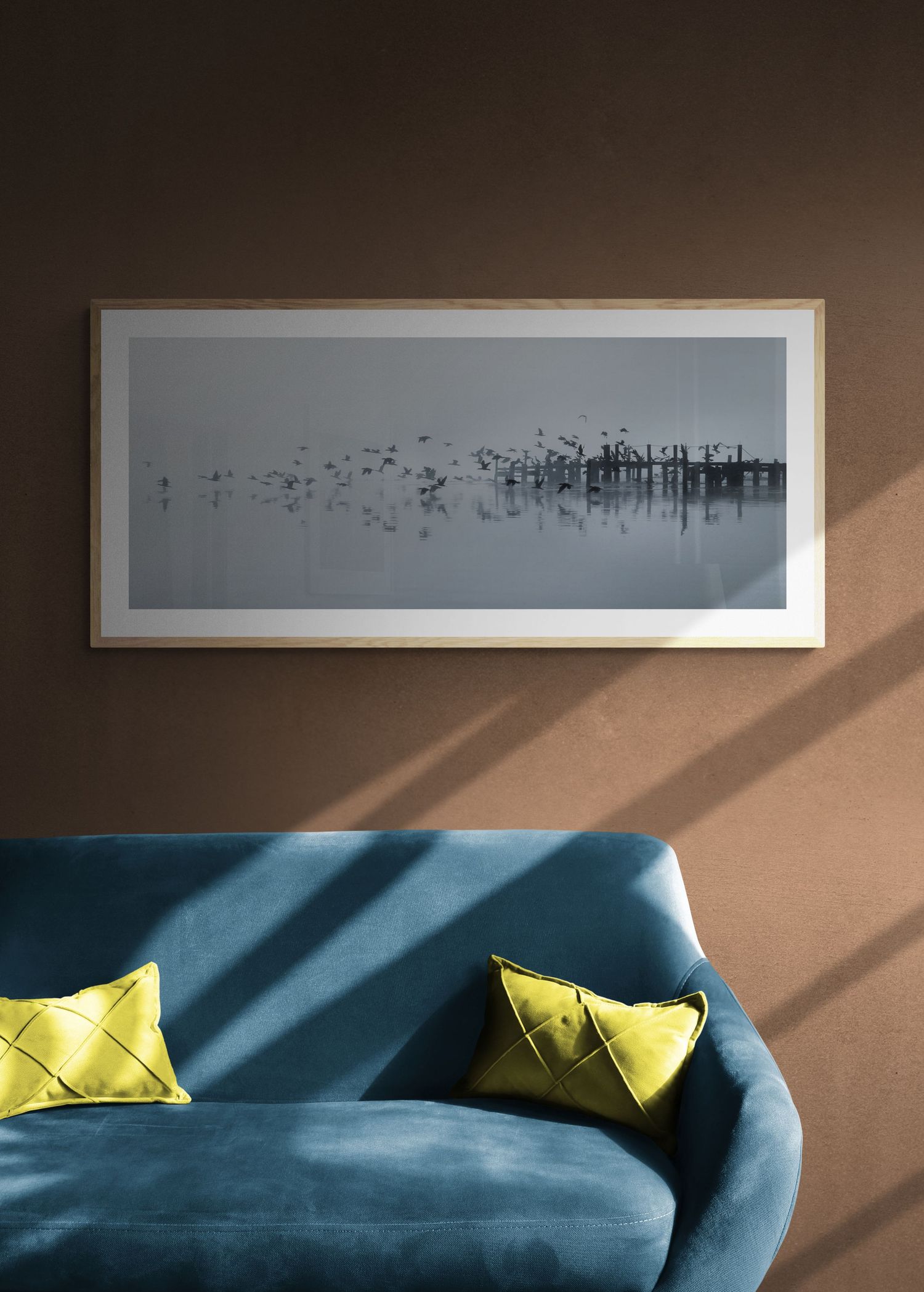 Minimalist black and white landscape artwork above a teal velvet sofa with yellow accent pillows.