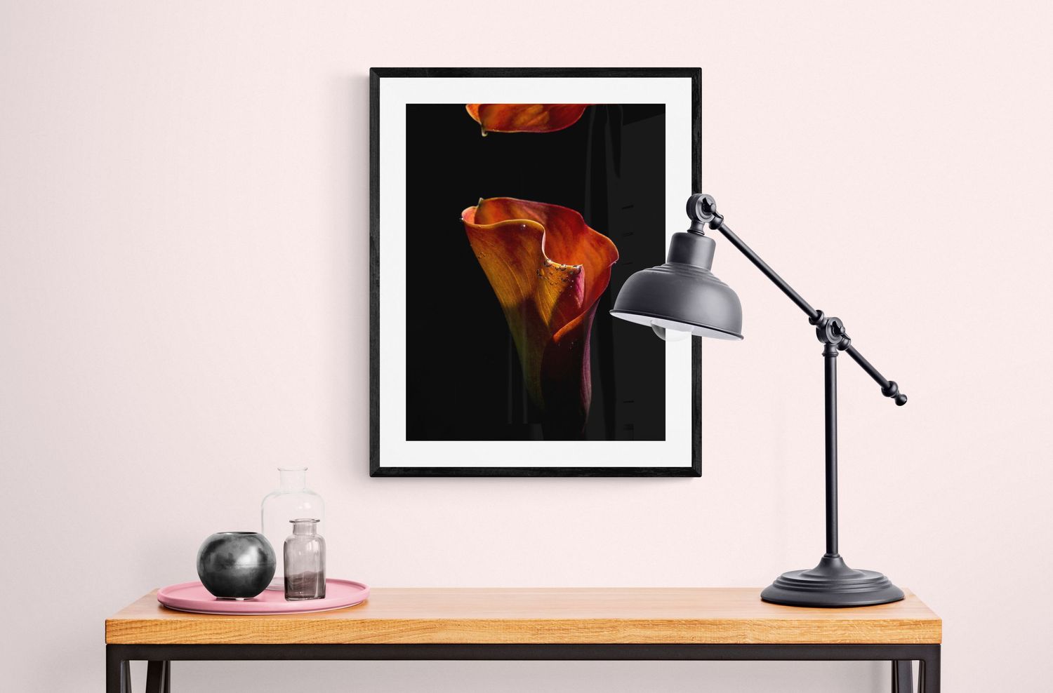 Dramatic close-up photograph of orange calla lilies against black background on wooden desk.
