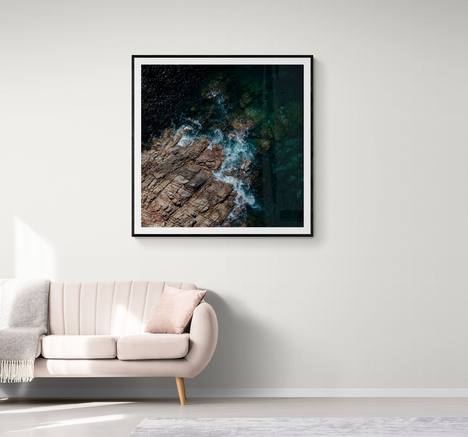 Aerial coastal photograph showing rocky shoreline and turquoise waters above pink sofa.