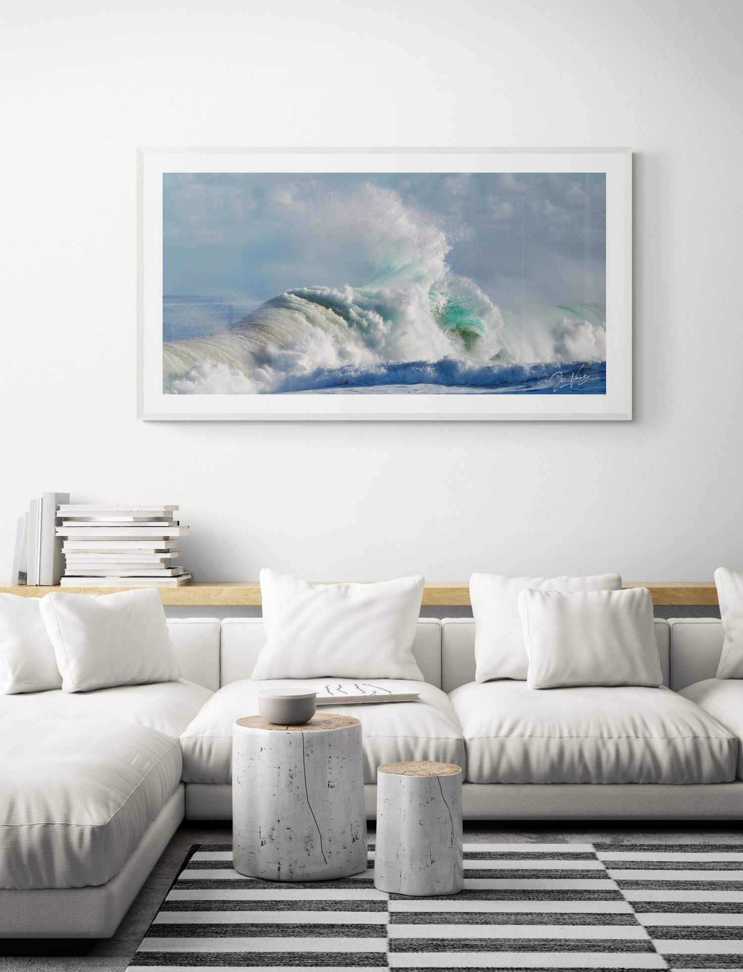 White coastal living room with dramatic ocean wave photograph above a sectional sofa.