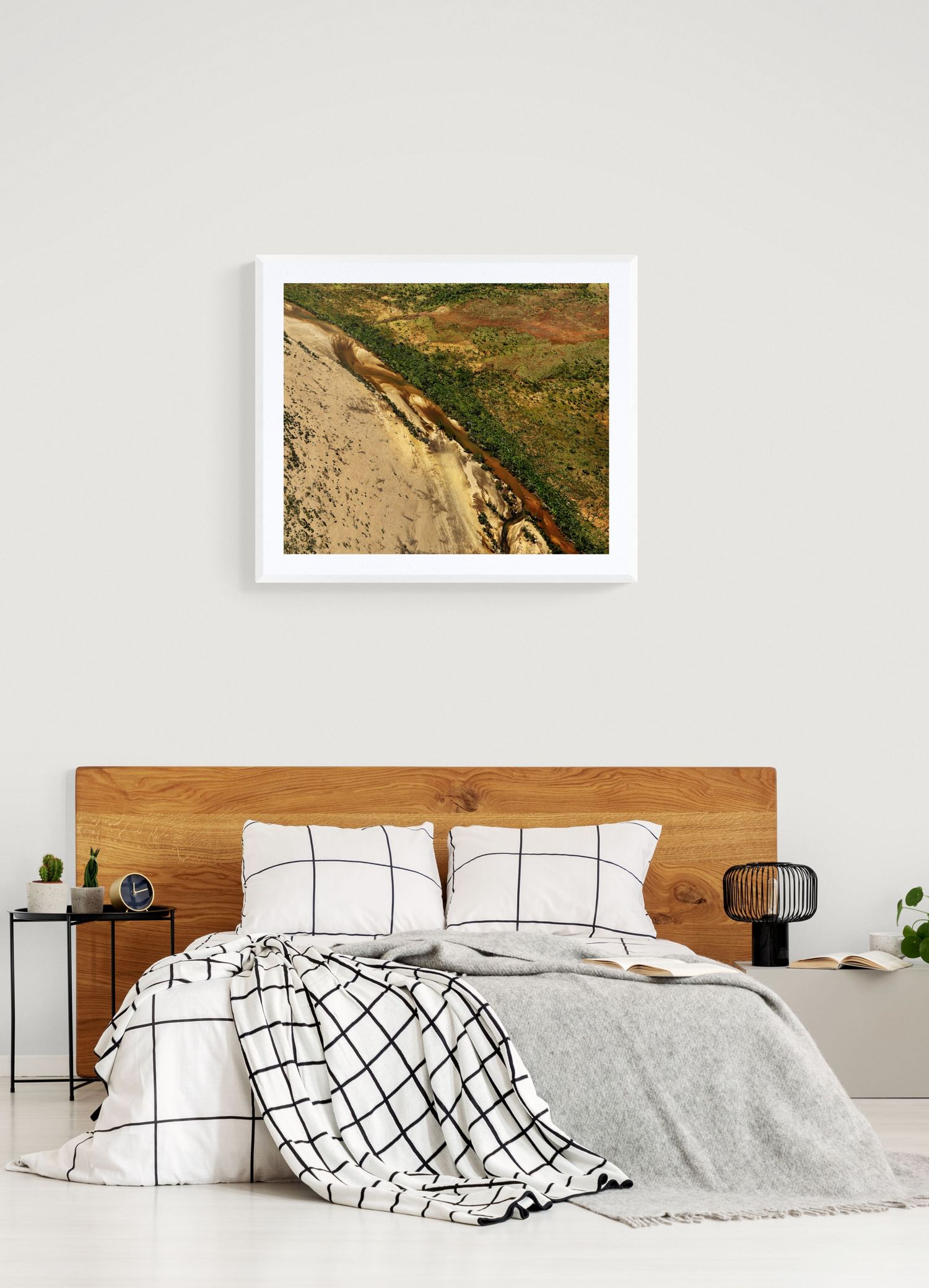 Landscape photograph of desert cliffs and vegetation mounted above modern bed with geometric patterns.