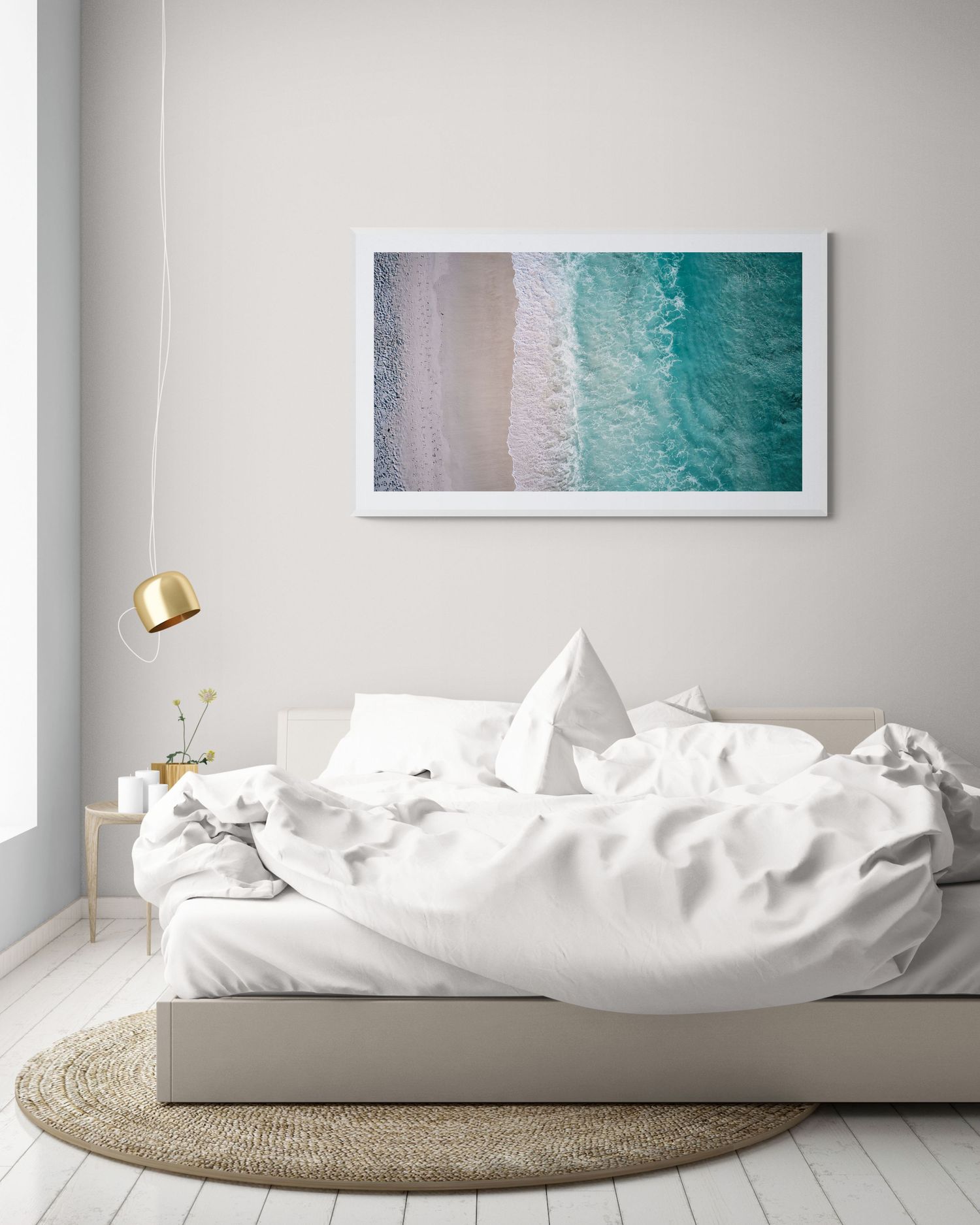 Aerial beach photograph showing turquoise waters meeting sandy shore, displayed above unmade white bed.