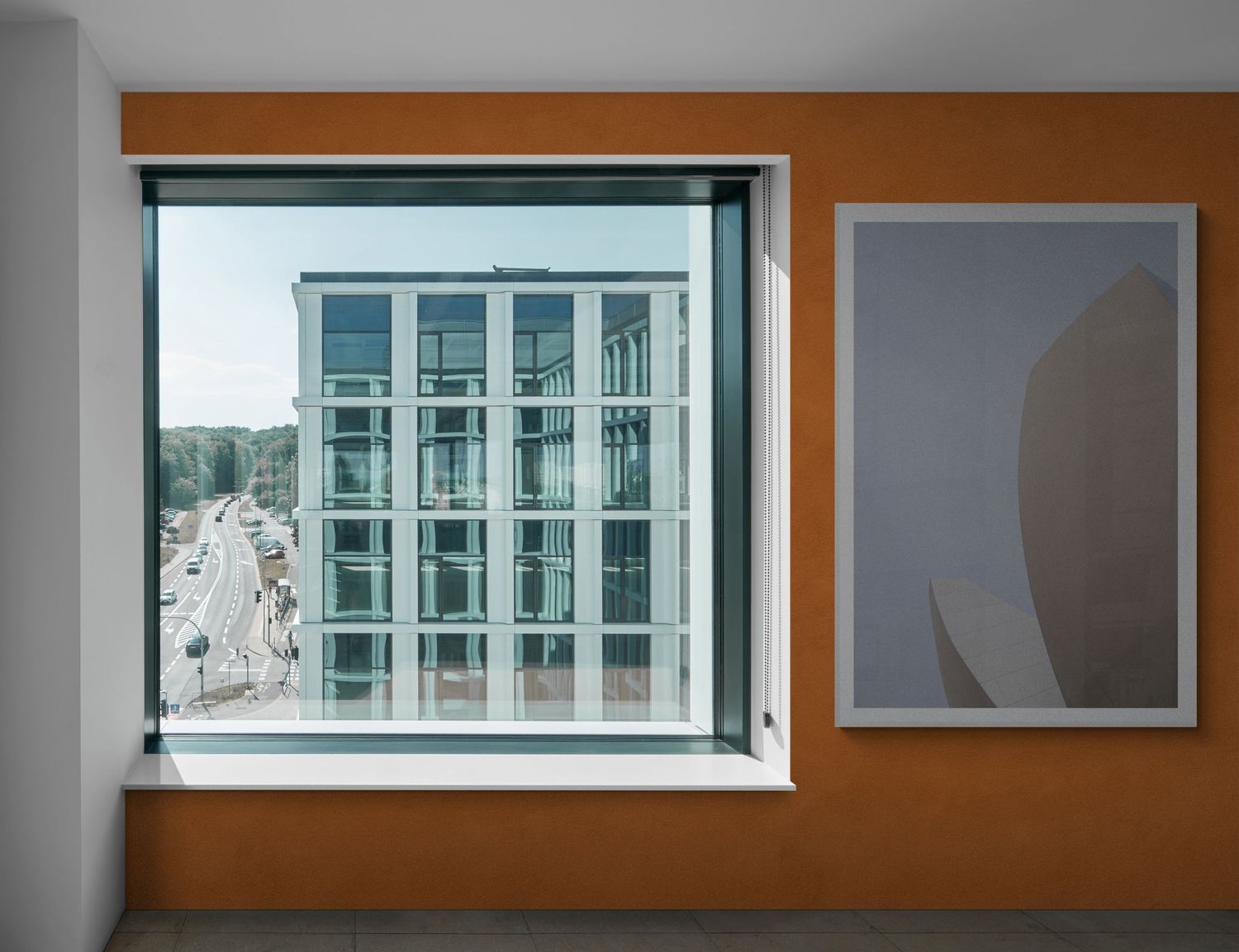 Modern apartment window view with geometric building facade and abstract wall art.