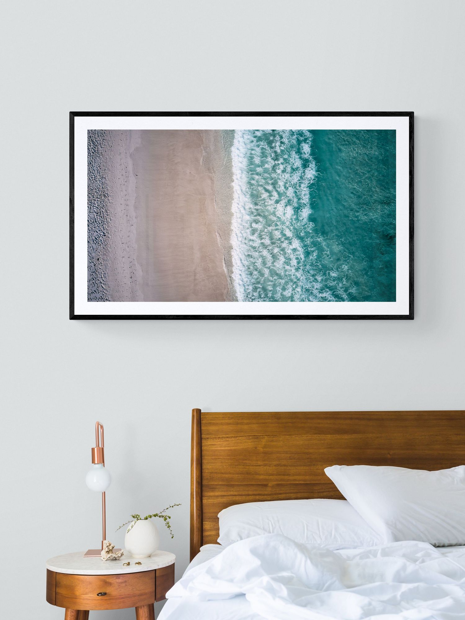 Aerial beach photograph showing turquoise waters meeting sandy shoreline in modern bedroom setting.