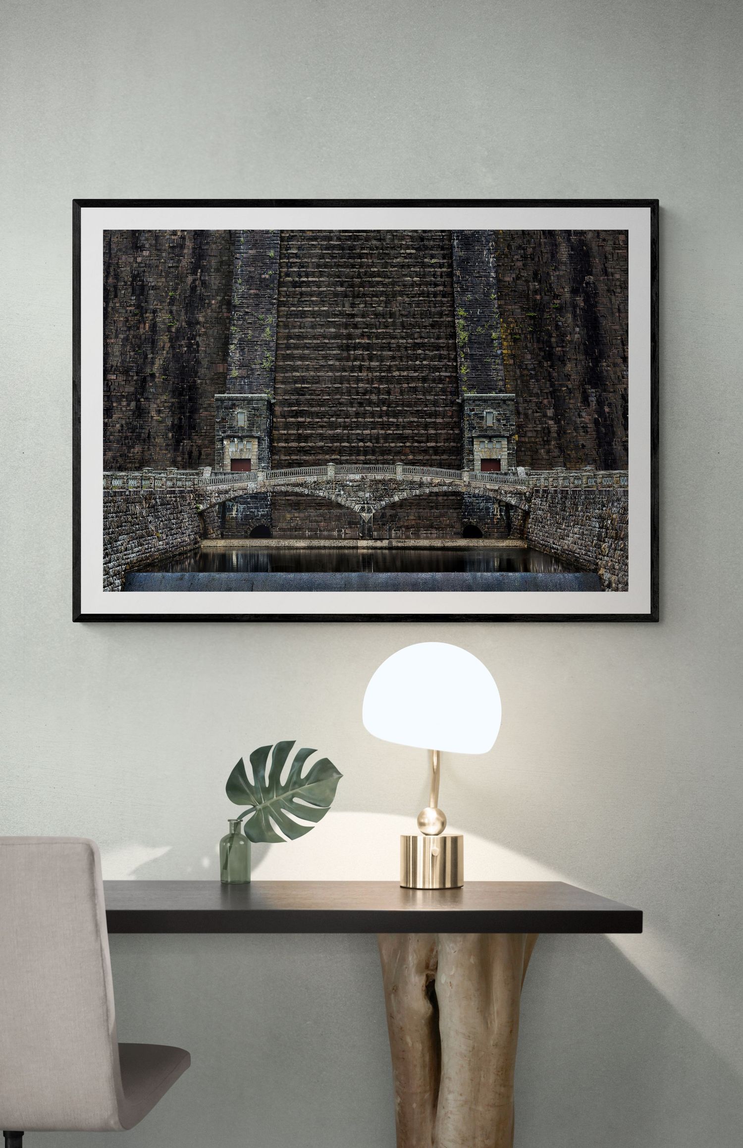 Black and white architectural photograph of stone bridge and dam structure above modern table lamp.