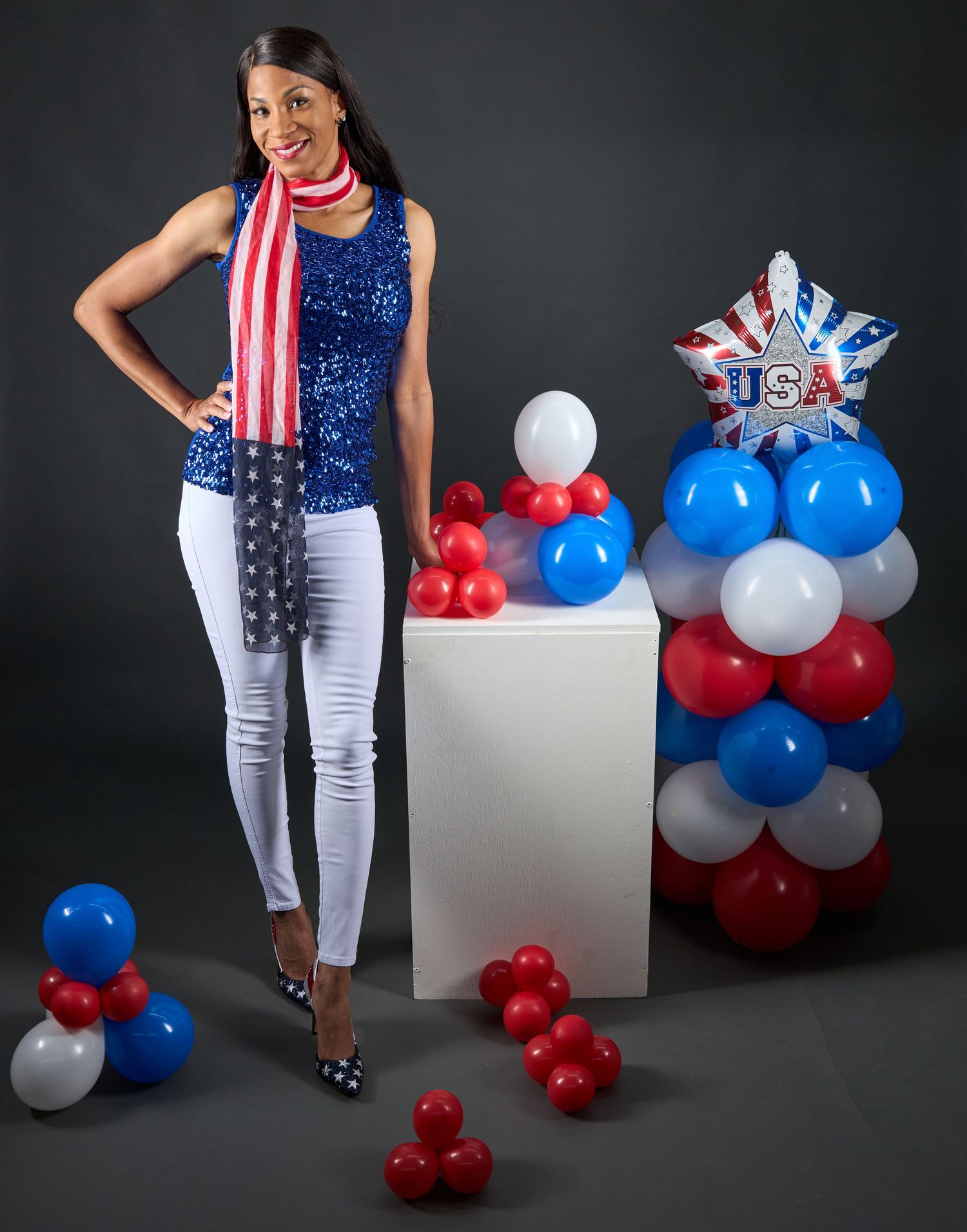 Patriotic themed photoshoot with red white and blue balloons against dark background.
