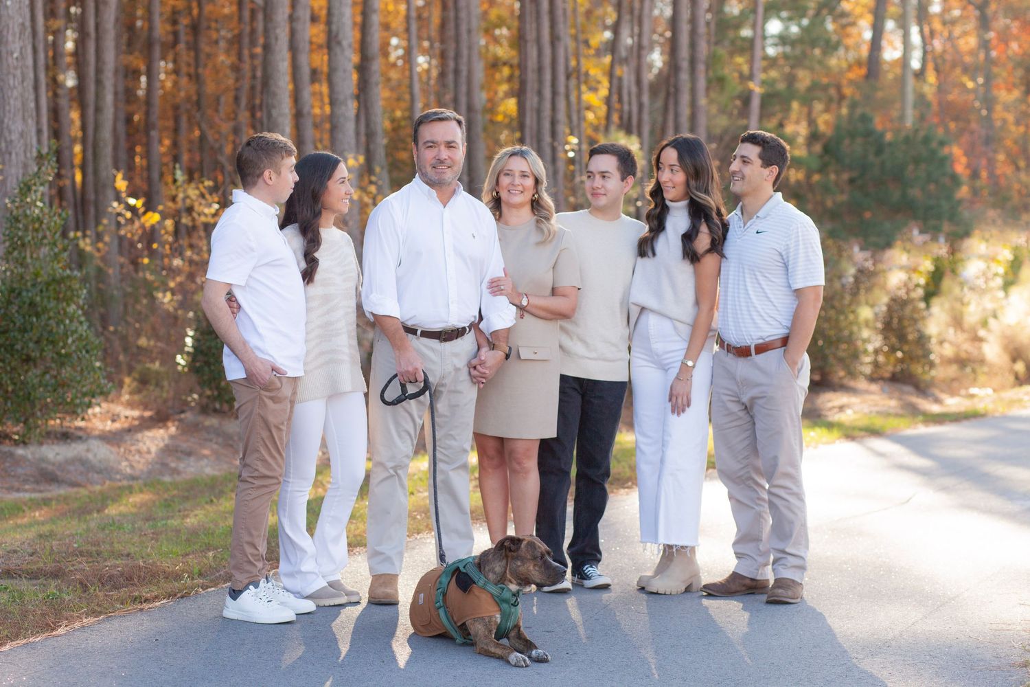A family in all tan clothing stands with their in front of foliage in Clayton, NC fall family photos.