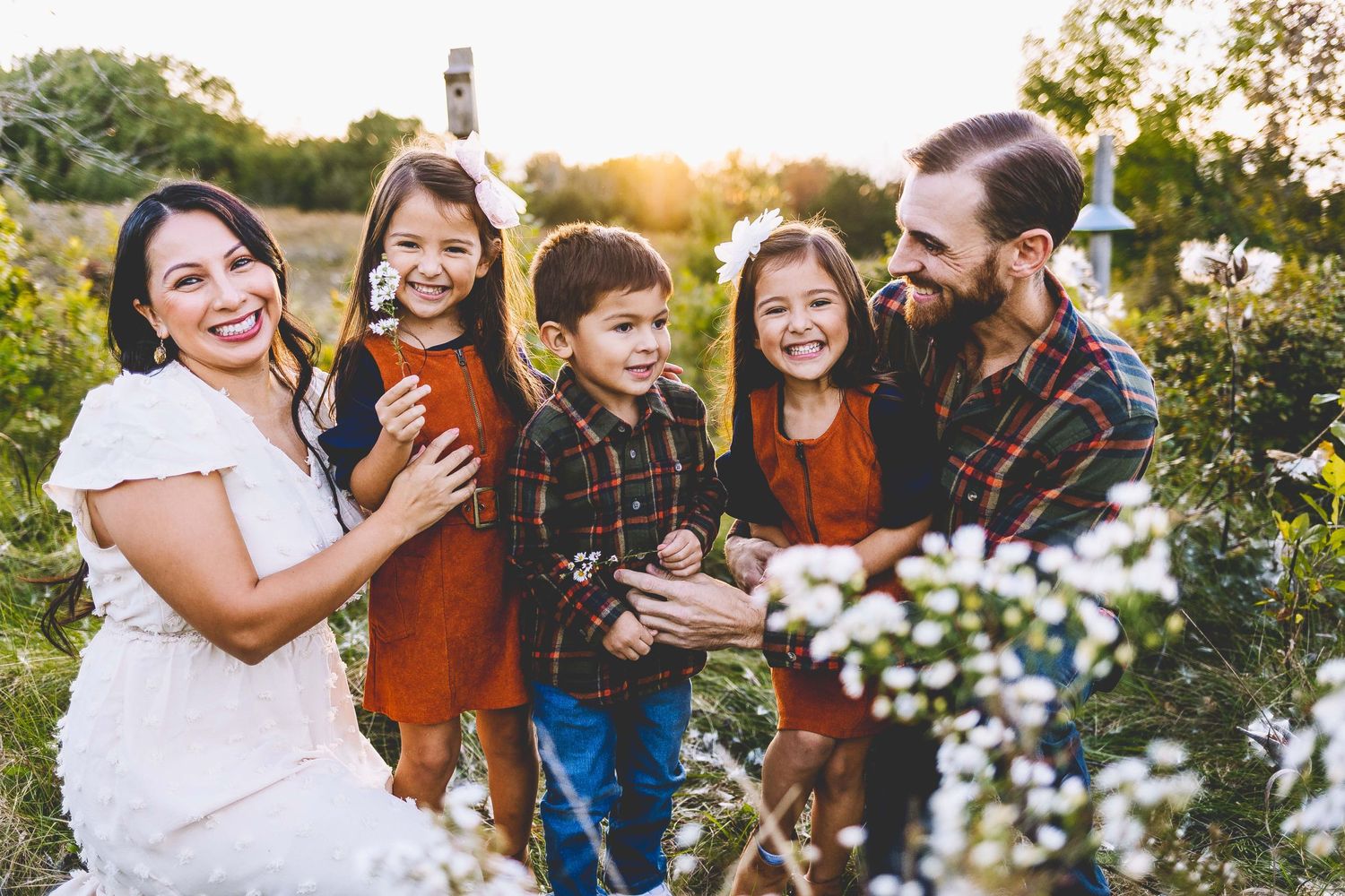 Candid famliy photoshoot done in a field of flowers with the golden hour light coming in behind familiy