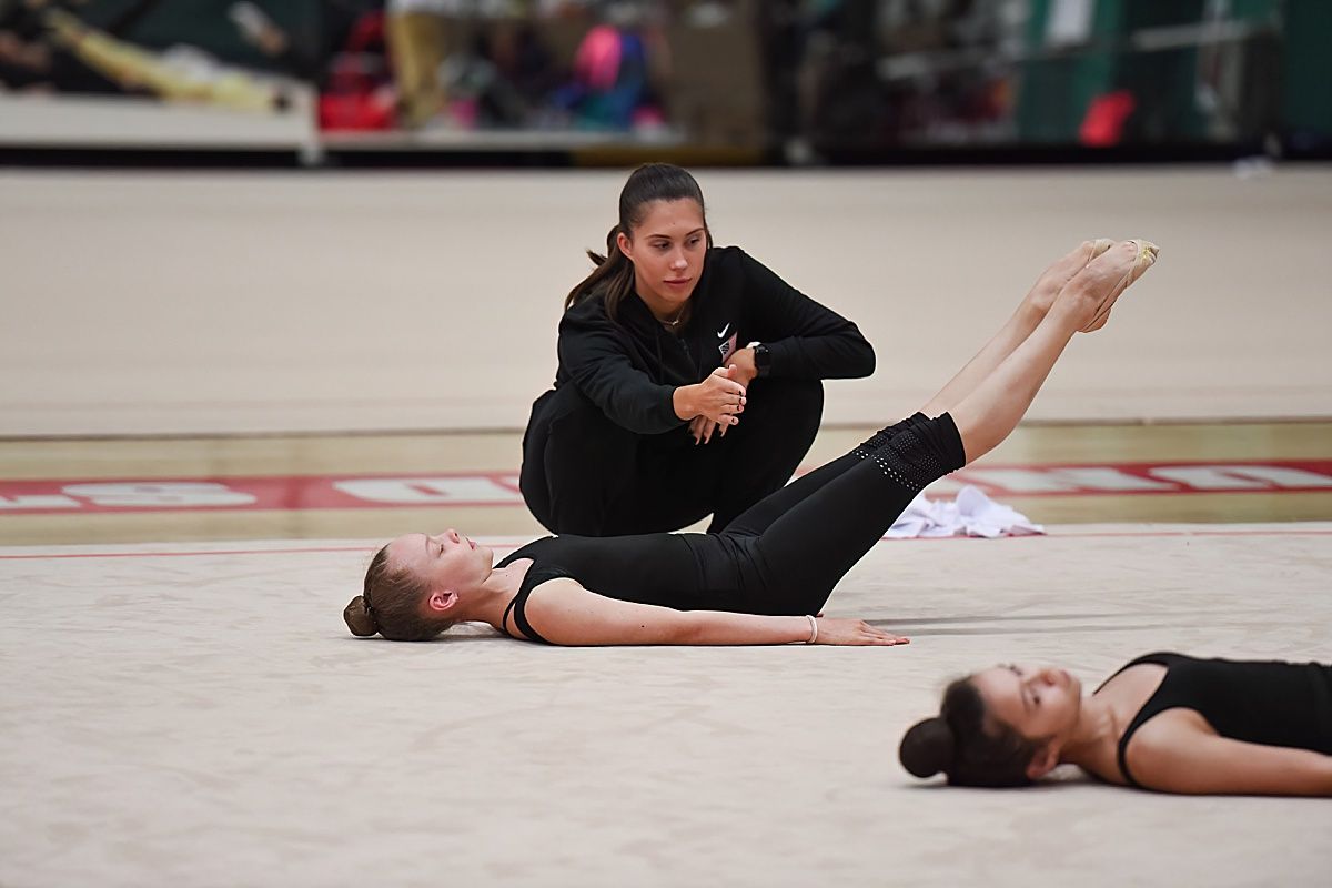 Rhythmic gymnastics coach with gymnast in warm up
