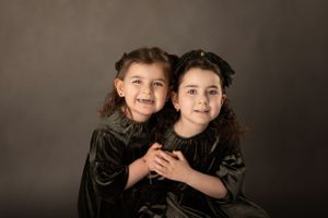 Studio portrait in dark velvet dresses against moody background.