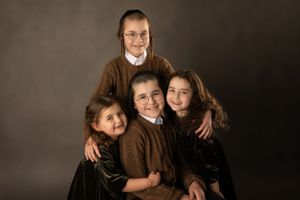 Studio portrait in brown and black matching outfits against dark background.
