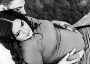 A black and white portrait captures a tender maternity moment between a couple.