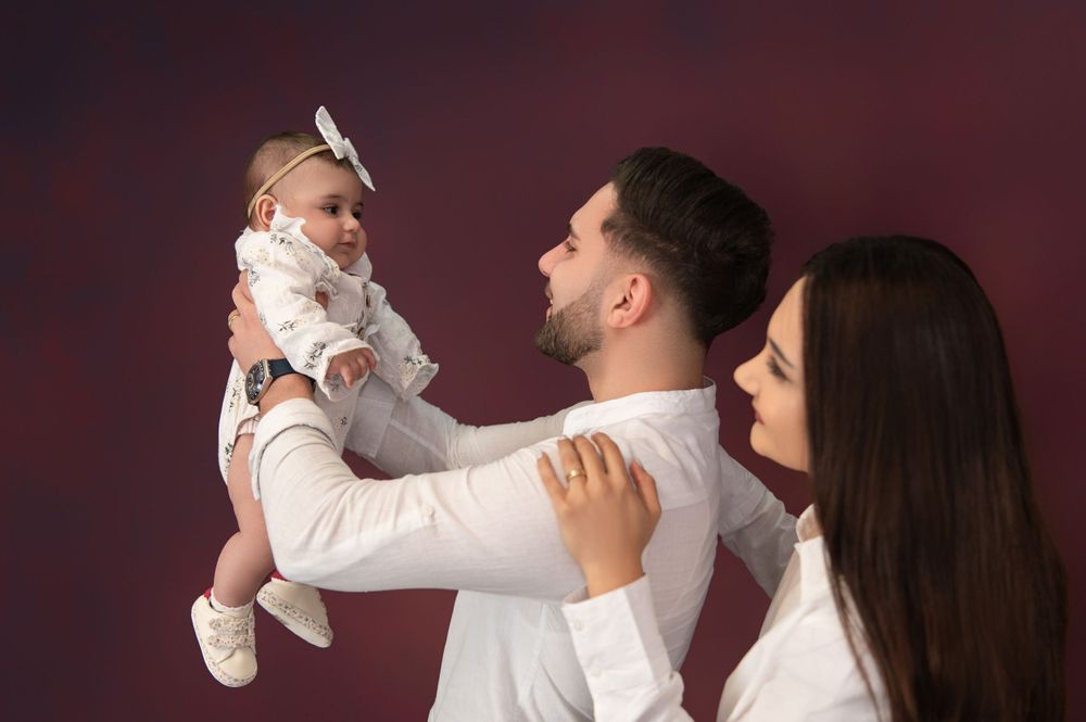 Family shares tender moment during professional photo session against dark backdrop.