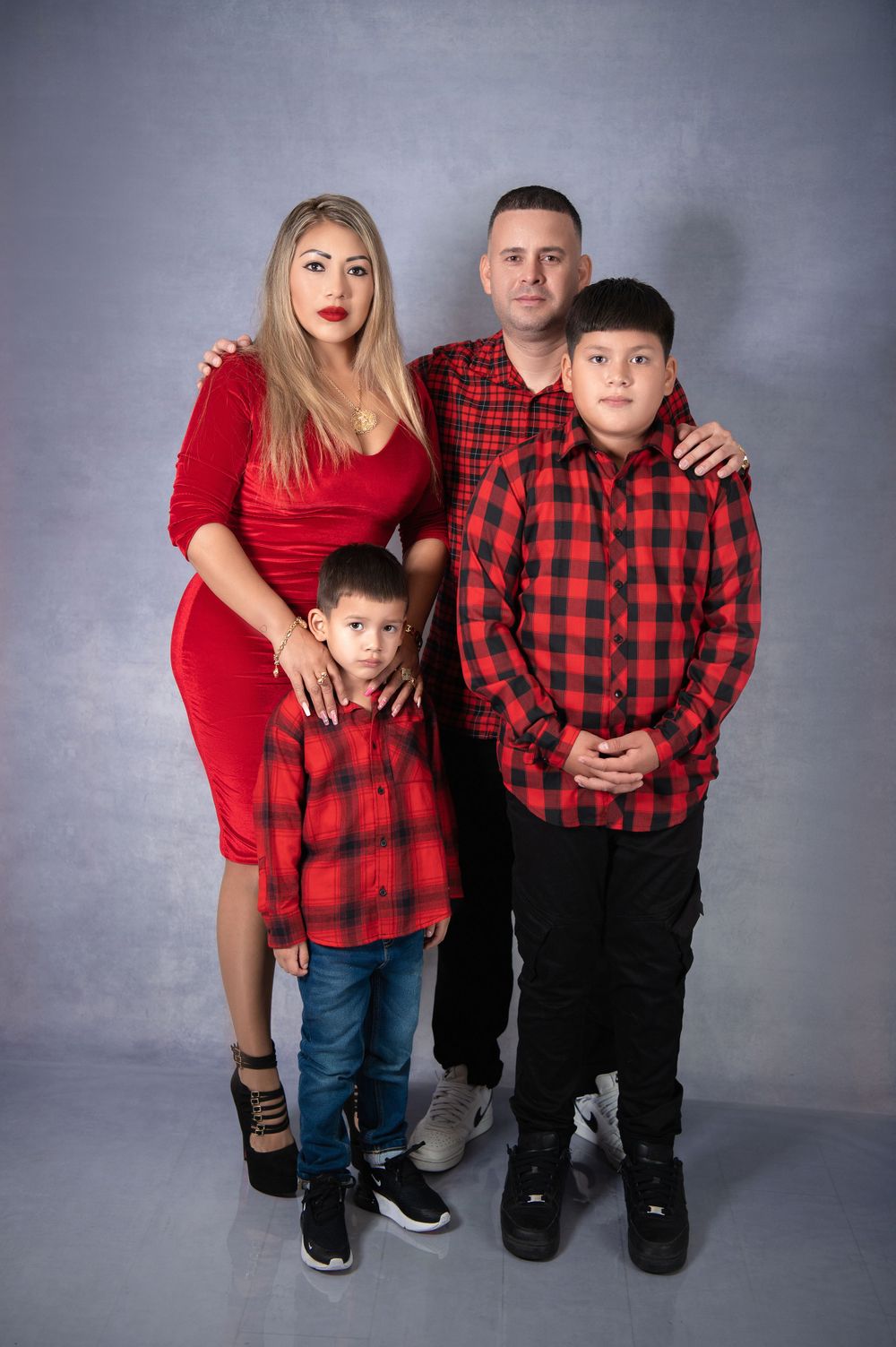 Studio family photo with matching red and black buffalo plaid theme.