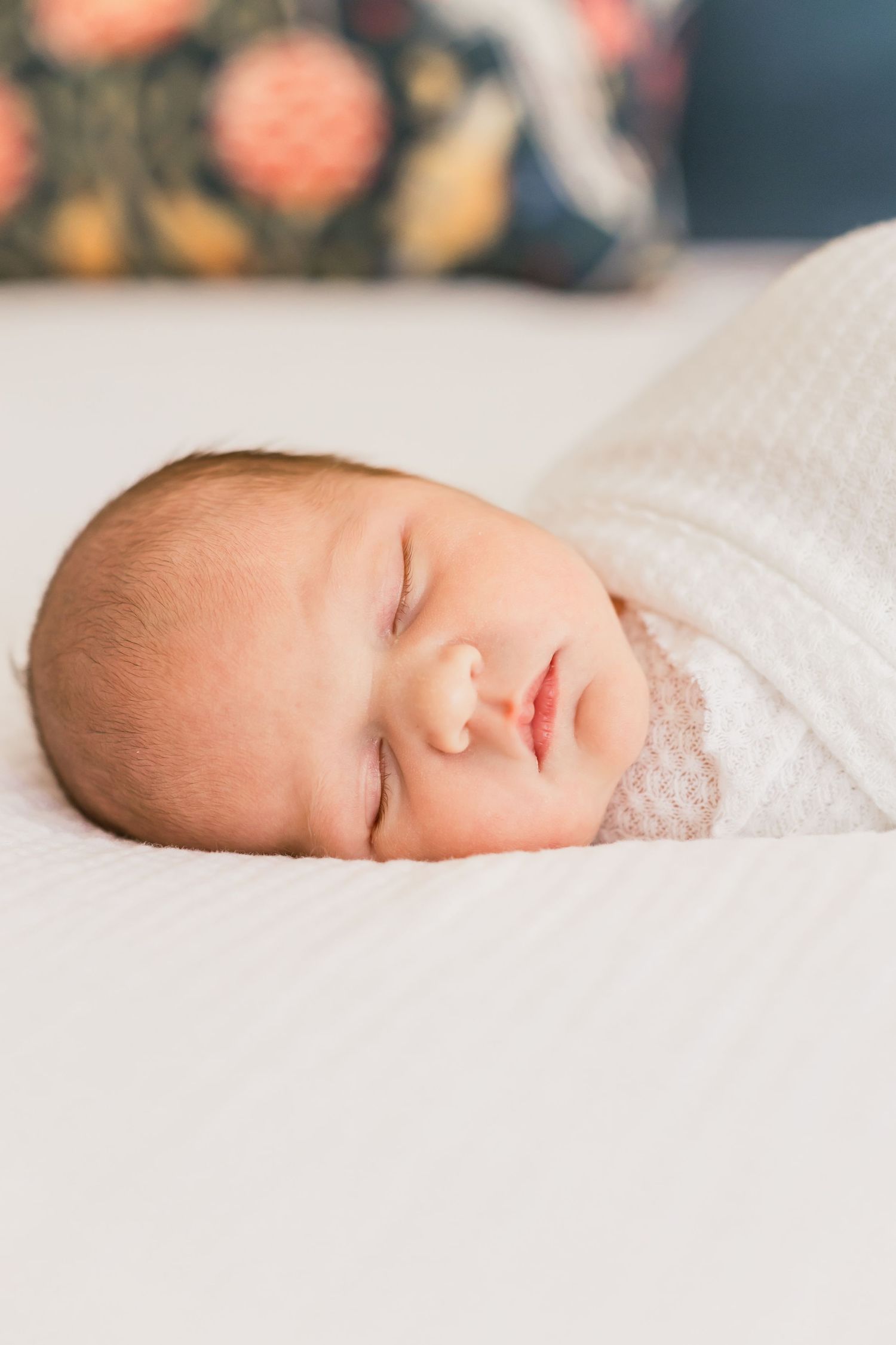 Close up of peaceful sleeping newborn baby swaddled in white.