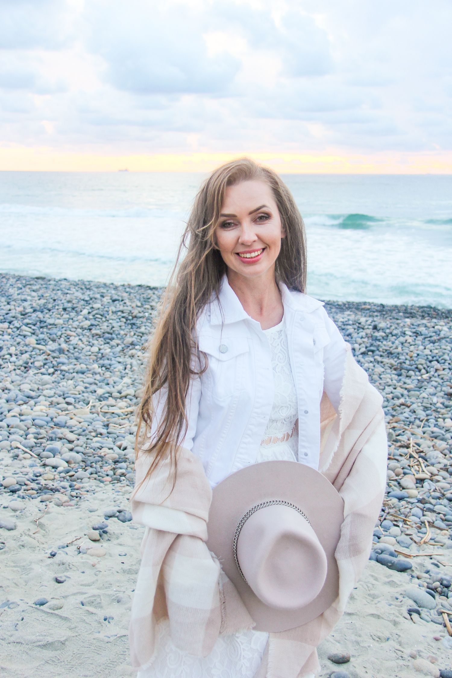 woman holding a beige hat and shawl at the beach