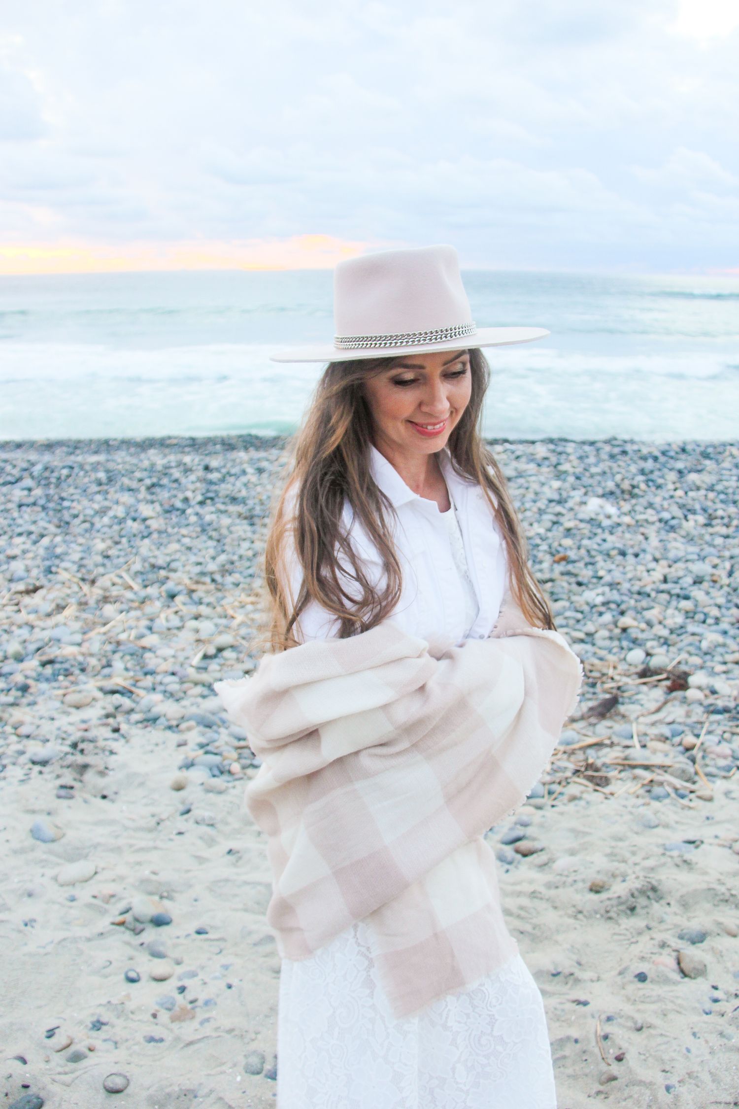 woman wearing a beige hat and shawl at the beach