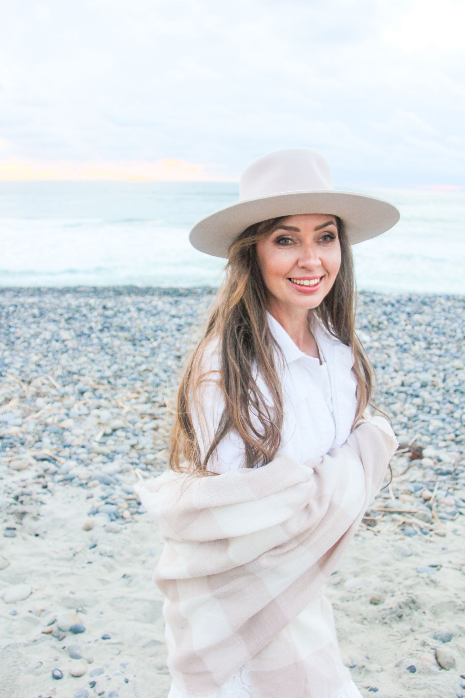 woman wearing a beige hat and shawl at the beach