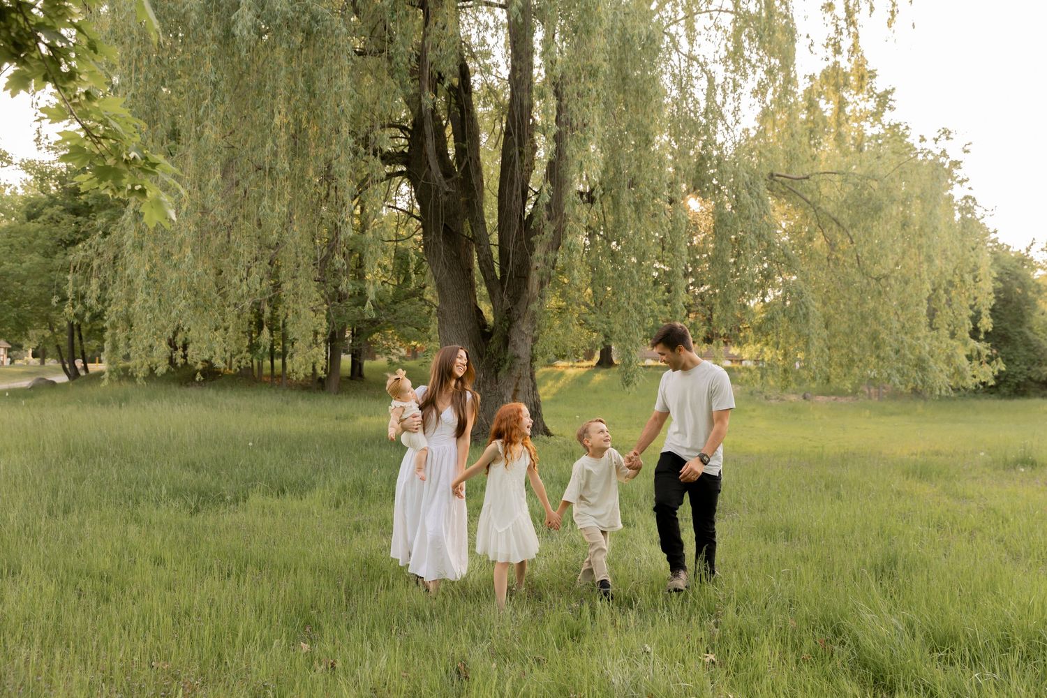 family of 5 holding hands, walking and laughing
