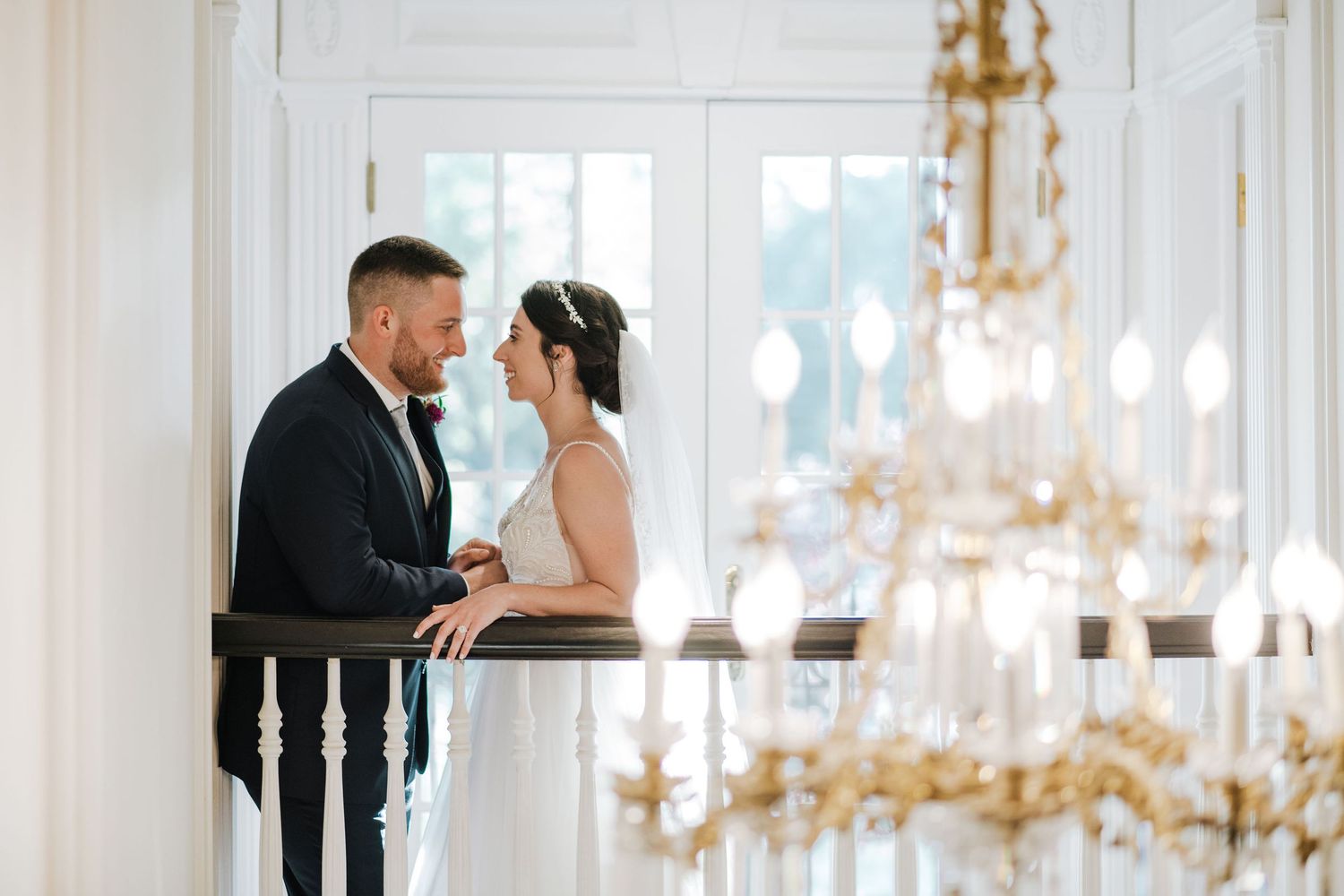 A romantic couple shares an intimate moment in an elegant room with a crystal chandelier in the foreground.