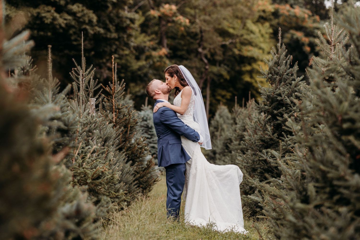 A beautiful wedding moment captured in a natural setting among evergreen trees.