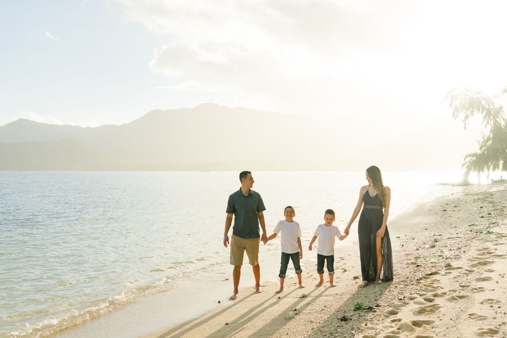 Family enjoying sunset together on a tropical beach with mountains in the distance. Oahu Family Photographer