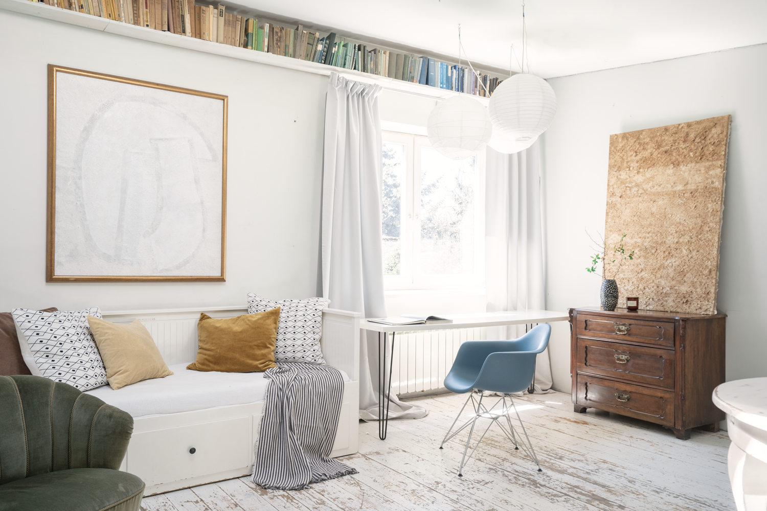 Modern minimalist bedroom interior with daybed, blue chair and wooden accents.