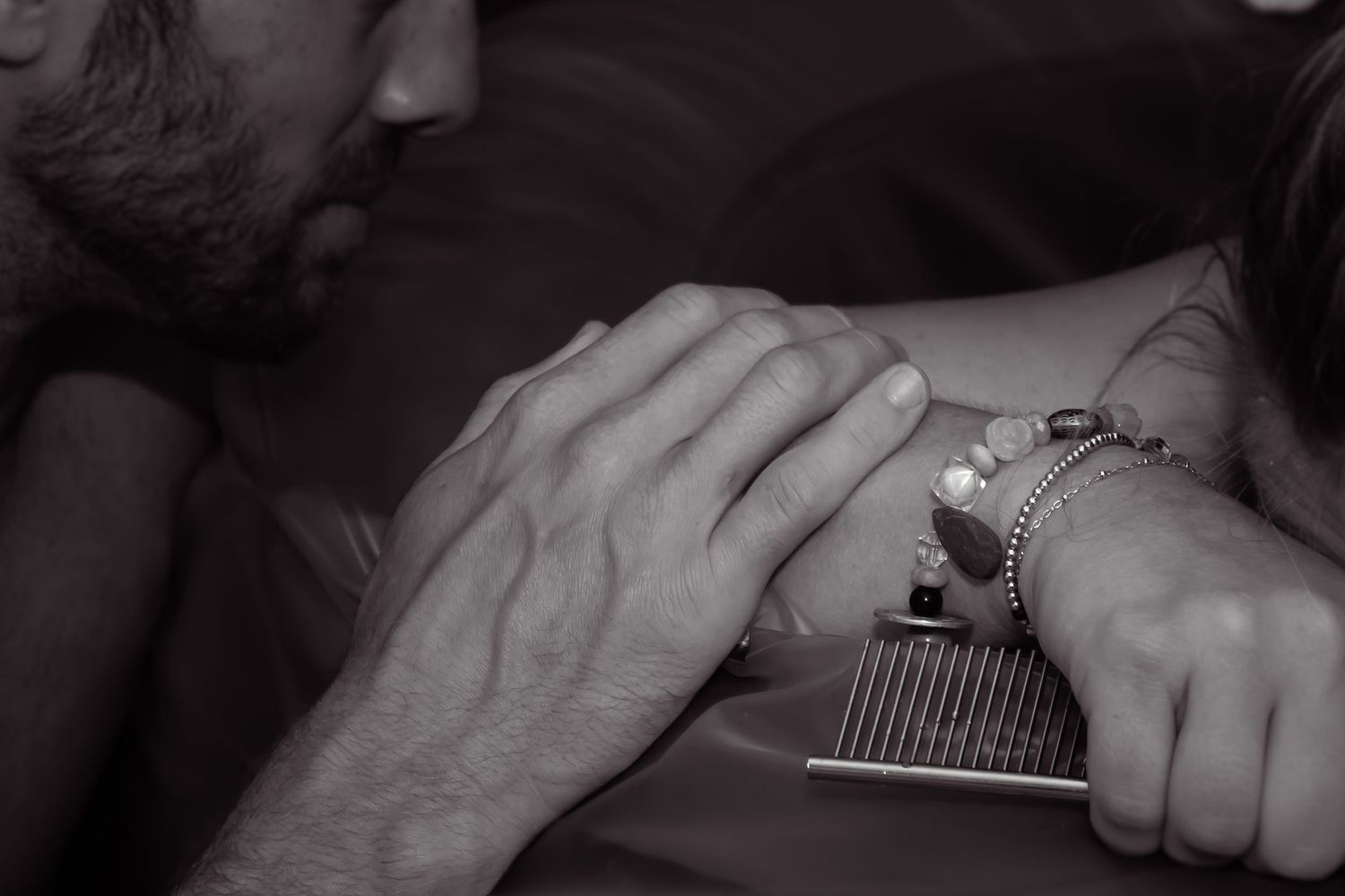 Black and white image of a man's hand on his wife's arm as she is in labor.