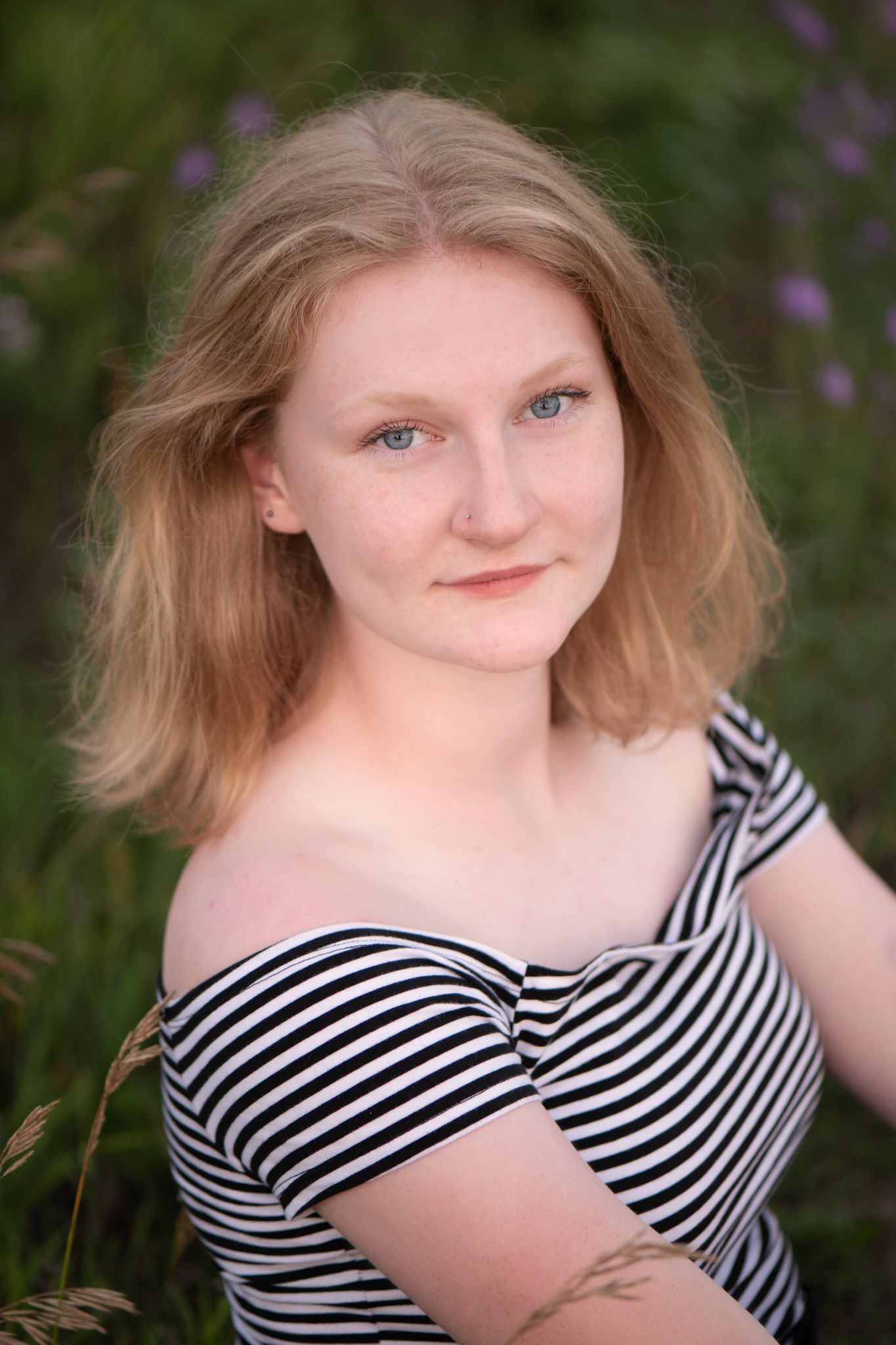 Outdoor portrait in striped top with purple flowers in background.