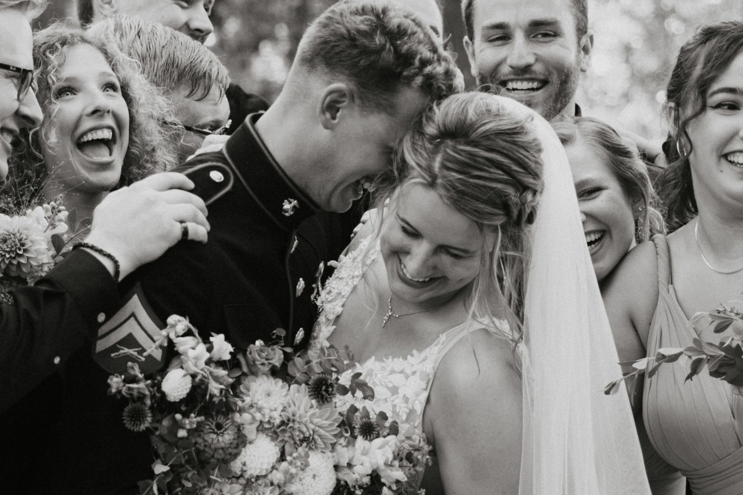 Wedding party laughing together outdoors in black and white photography.