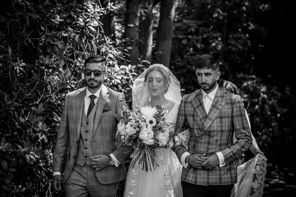 Joyful wedding party celebrates outdoors in elegant formal attire at a garden venue.