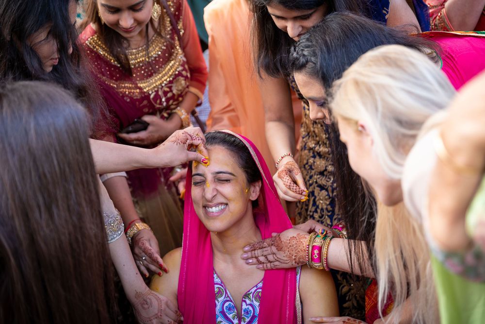Colorful cultural pre-wedding ceremony with women gathering to apply traditional decorations.