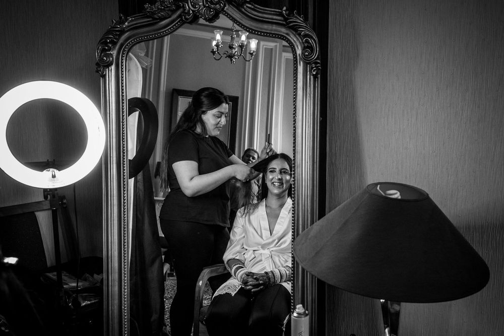 Black and white image of wedding day preparations with ring light and ornate mirror.