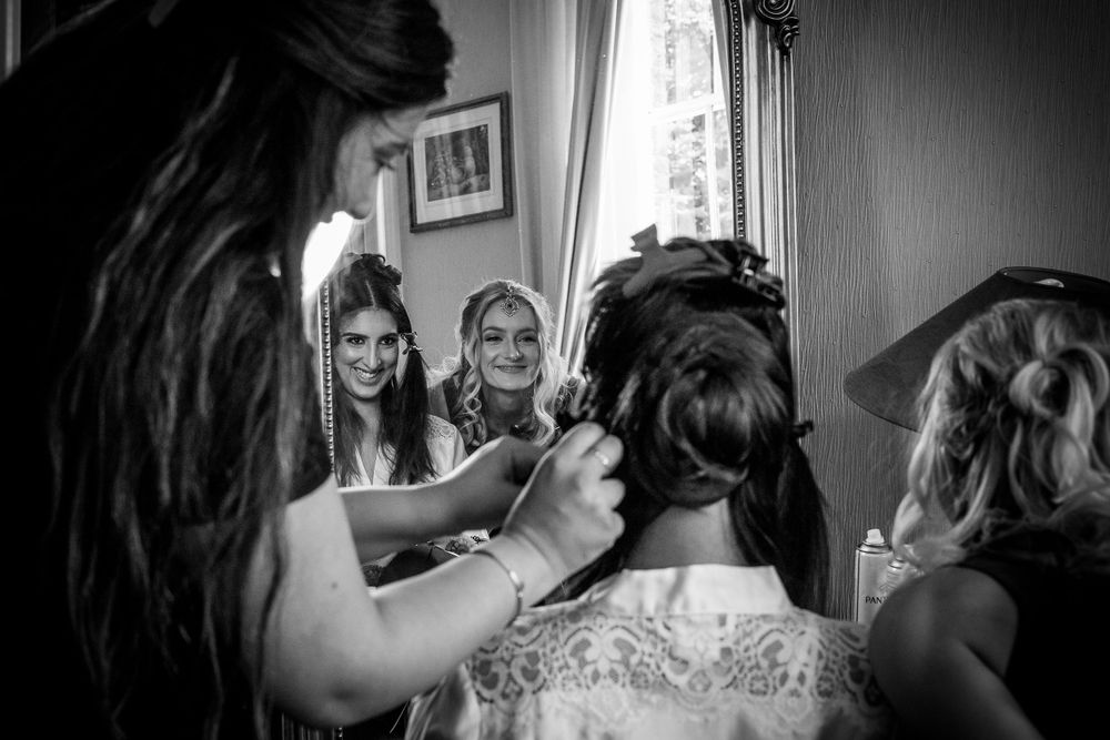 Black and white photo capturing wedding morning preparations with bridesmaids.