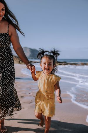 A heartwarming moment captured on a beach with a polka dot dress and yellow outfit visible against the waves.