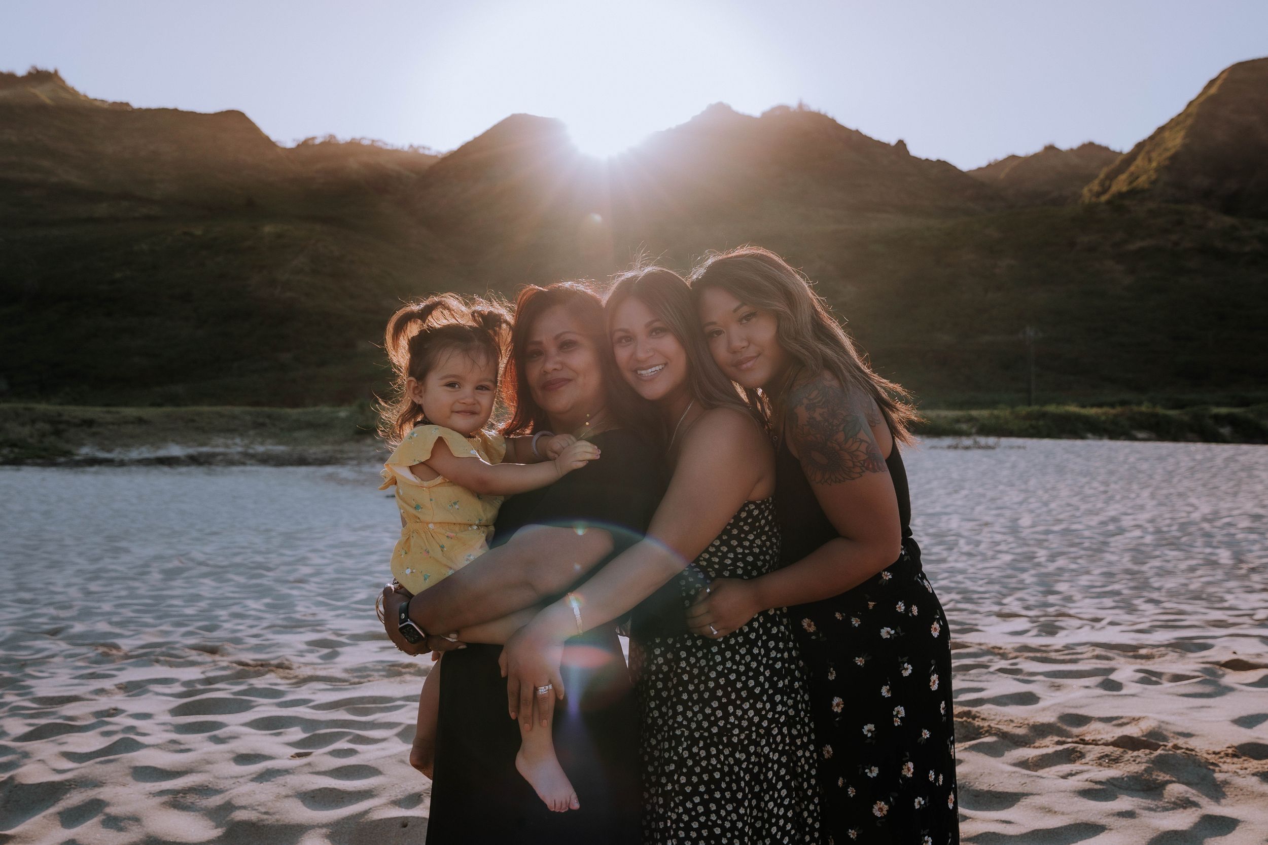 Silhouettes embrace against mountain backdrop during sunset at lakeside.